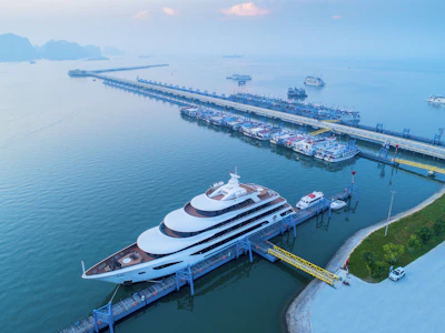 Luxury yacht docked at a long pier with boats.