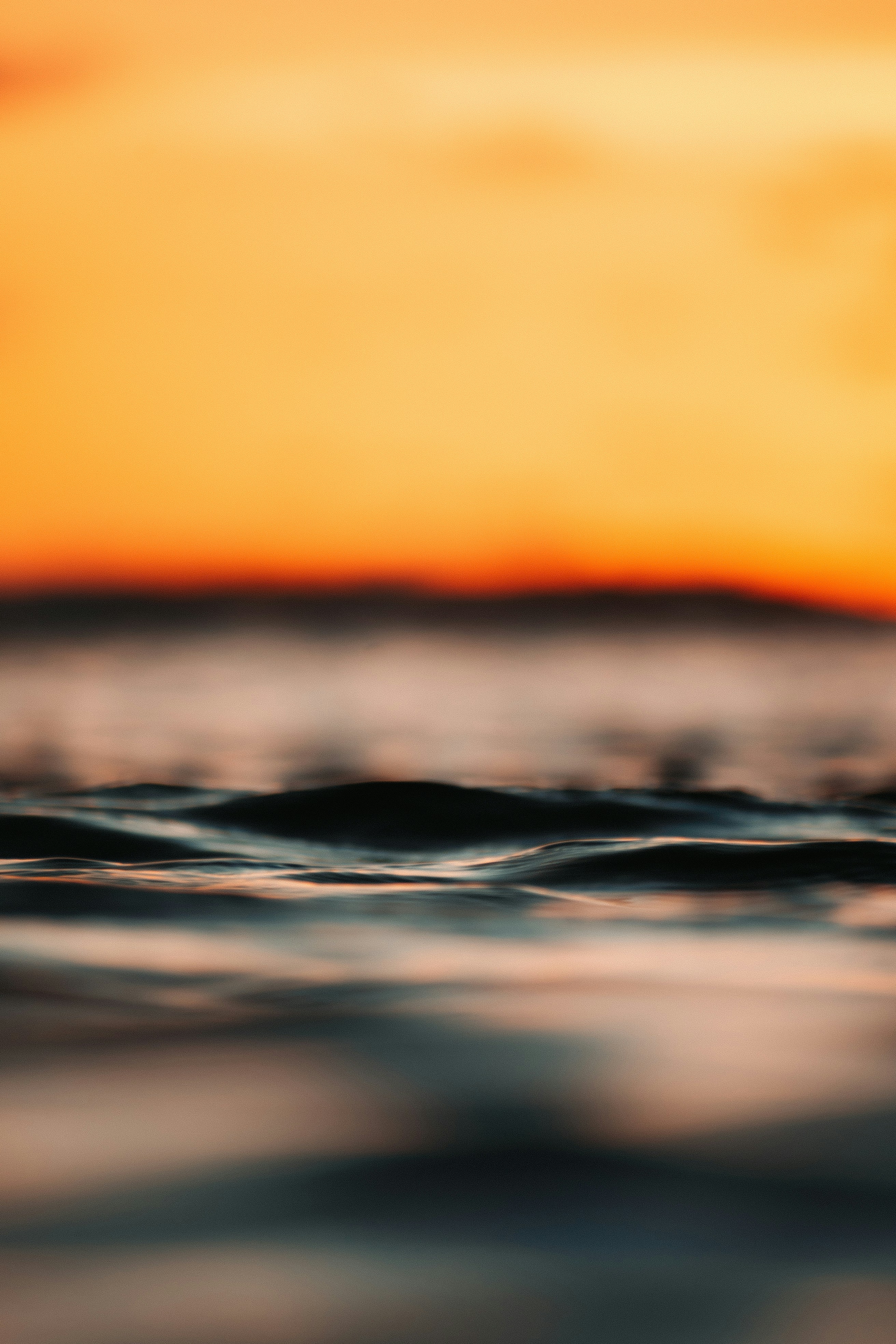 Calm ocean waves at sunset with orange sky
