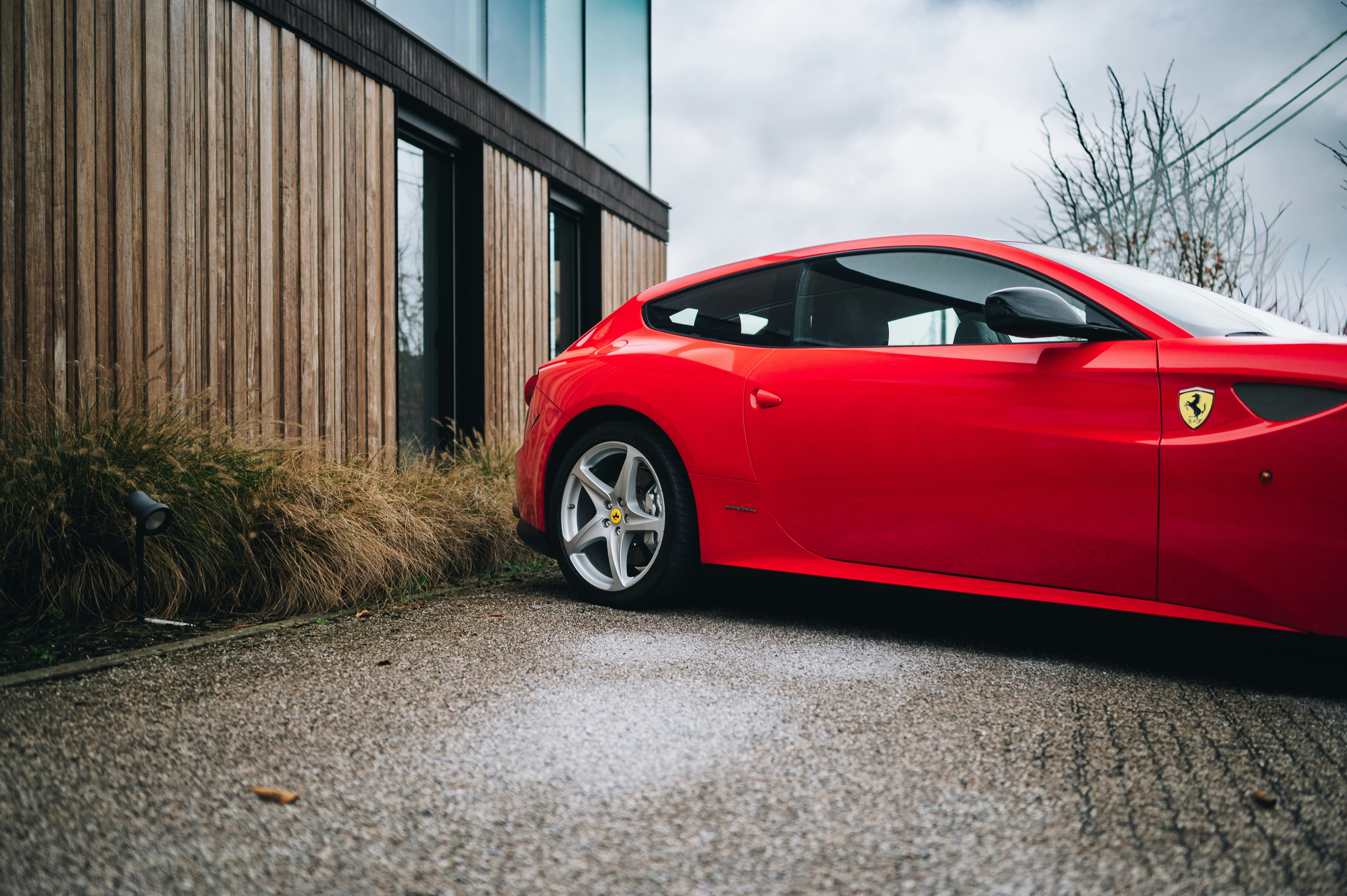 Roter Ferrari steht neben einem modernen Holzhaus.