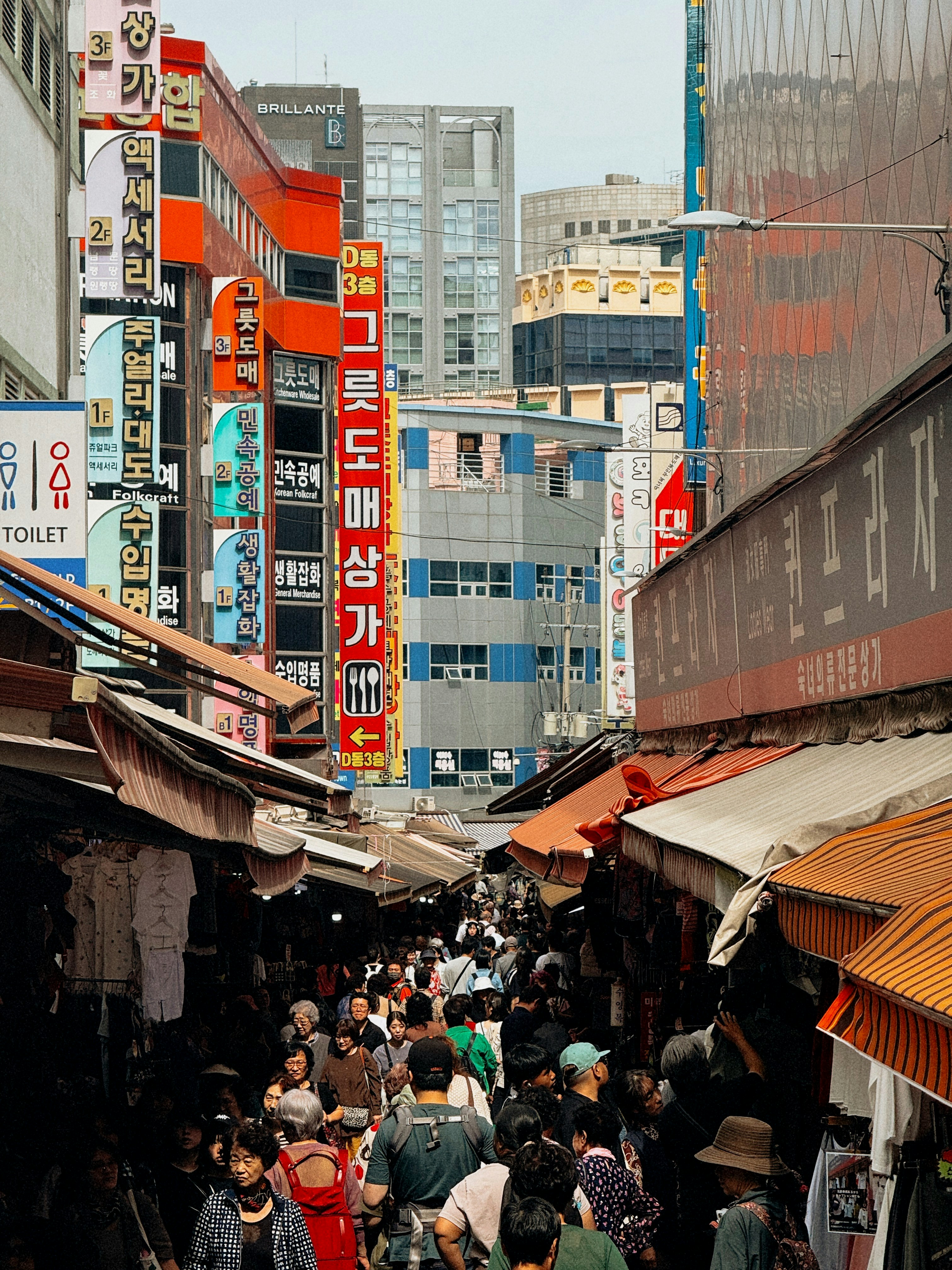 Ein überfüllter Straßenmarkt mit bunten Schildern und Gebäuden.