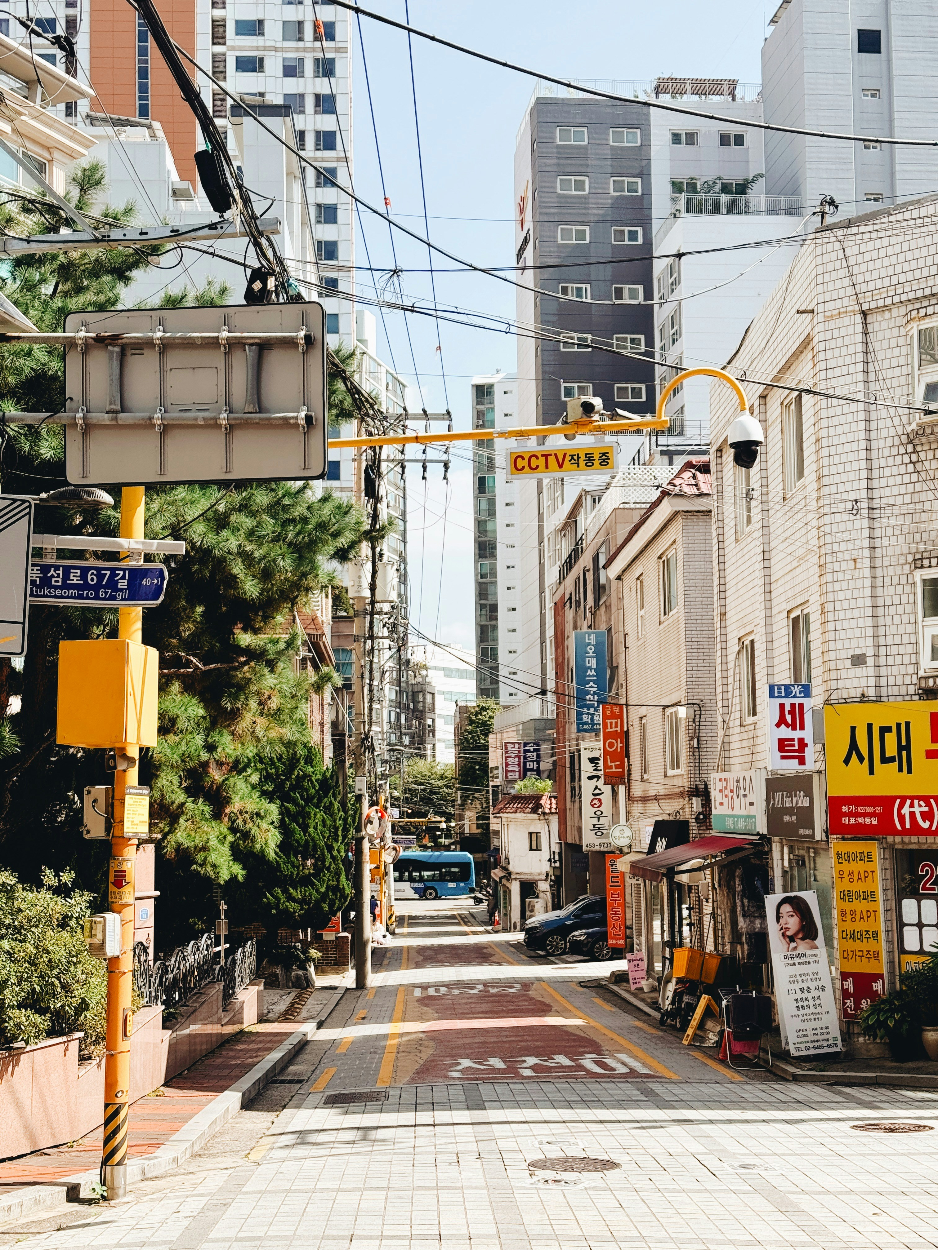 Straßenansicht mit Gebäuden, Kabeln und einem blauen Bus.