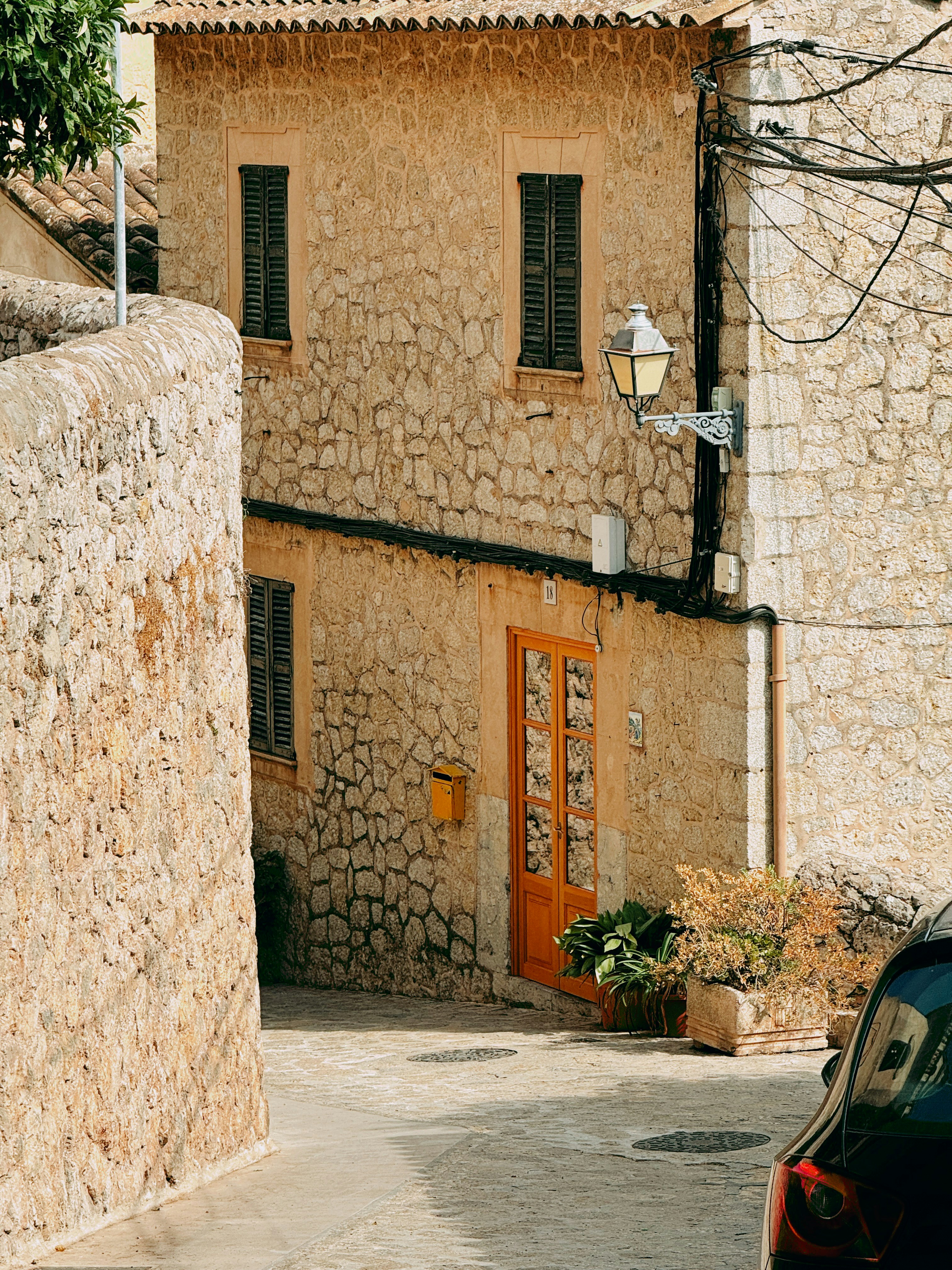 Steingebäude mit orangefarbener Tür in einer sonnigen Straße.