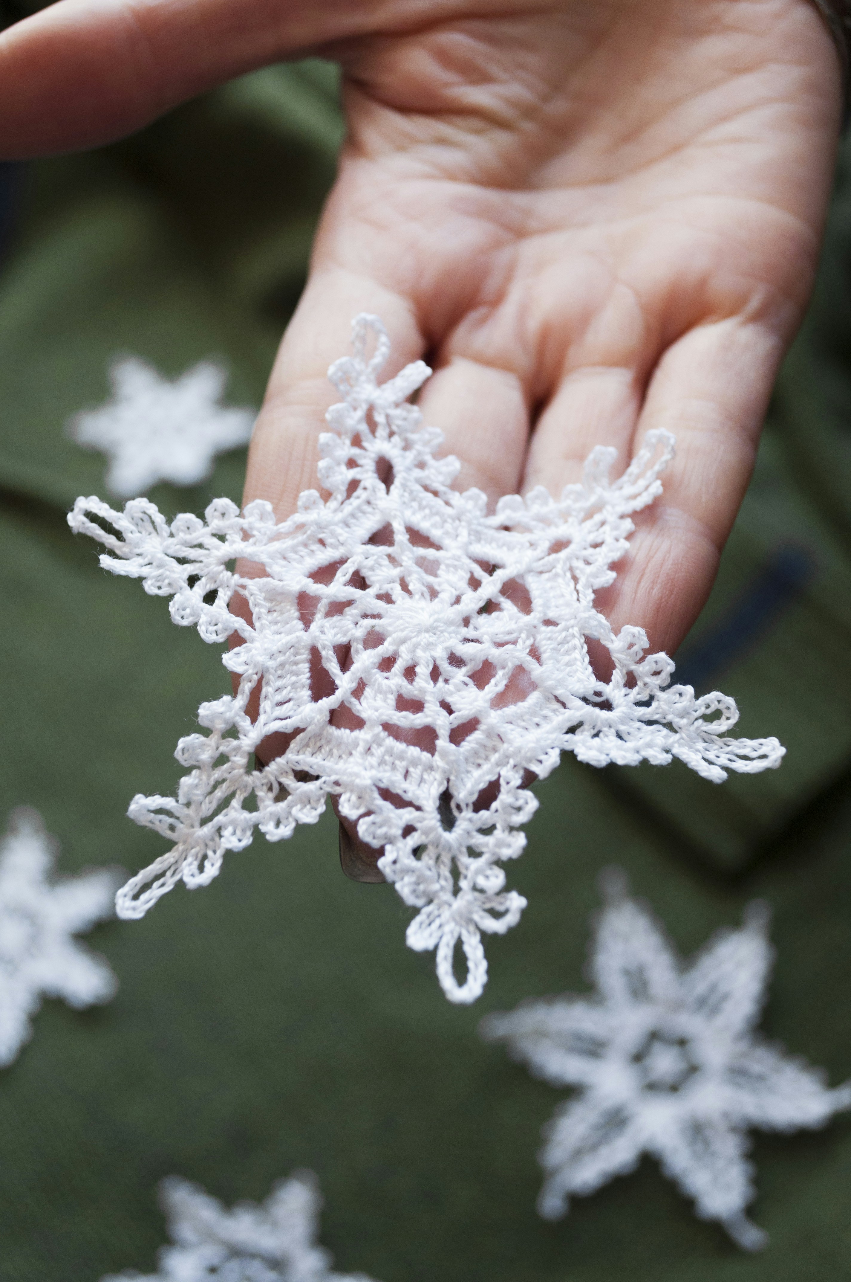 Hand holding delicate white lace snowflake decoration