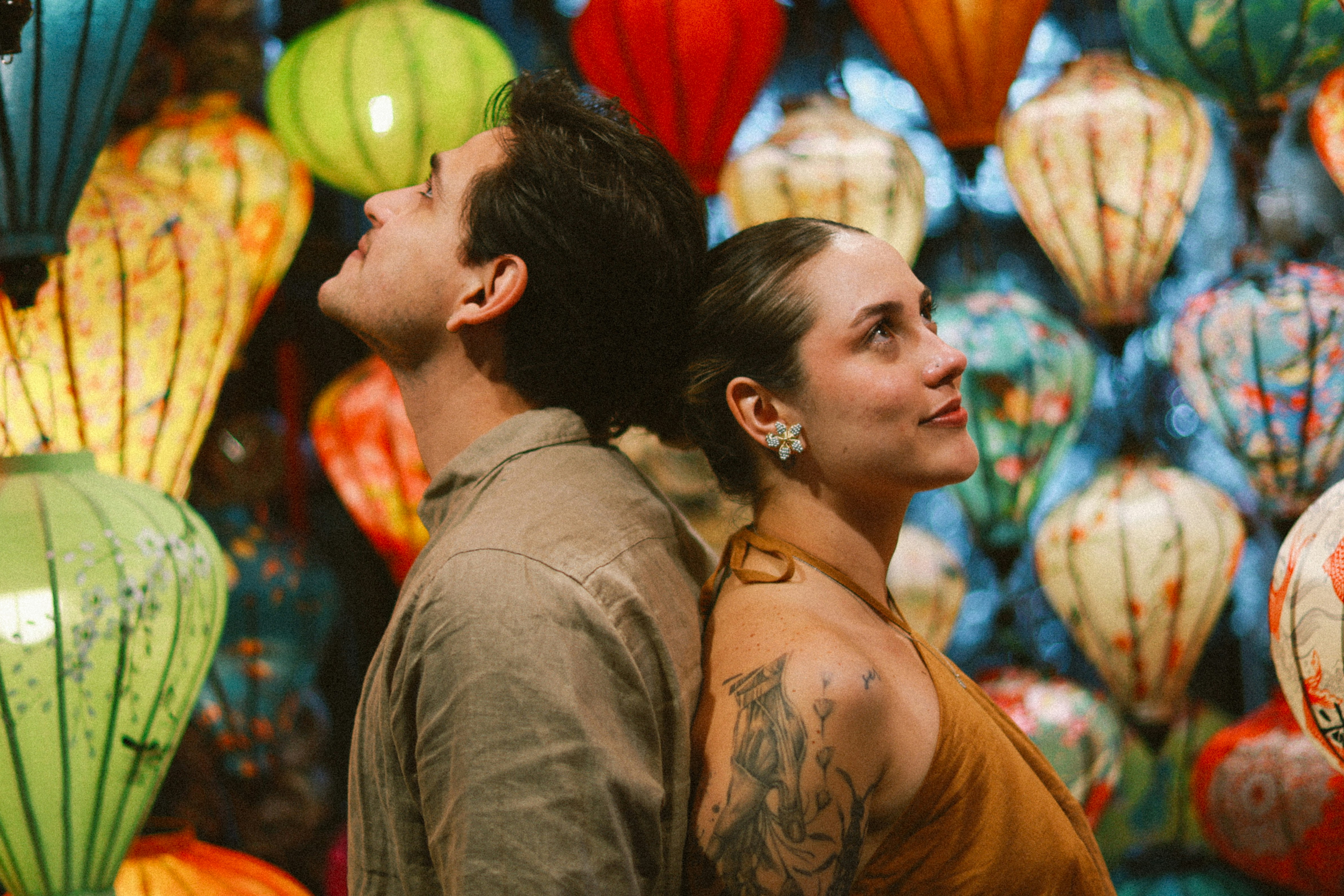 Couple looking up amidst colorful lanterns