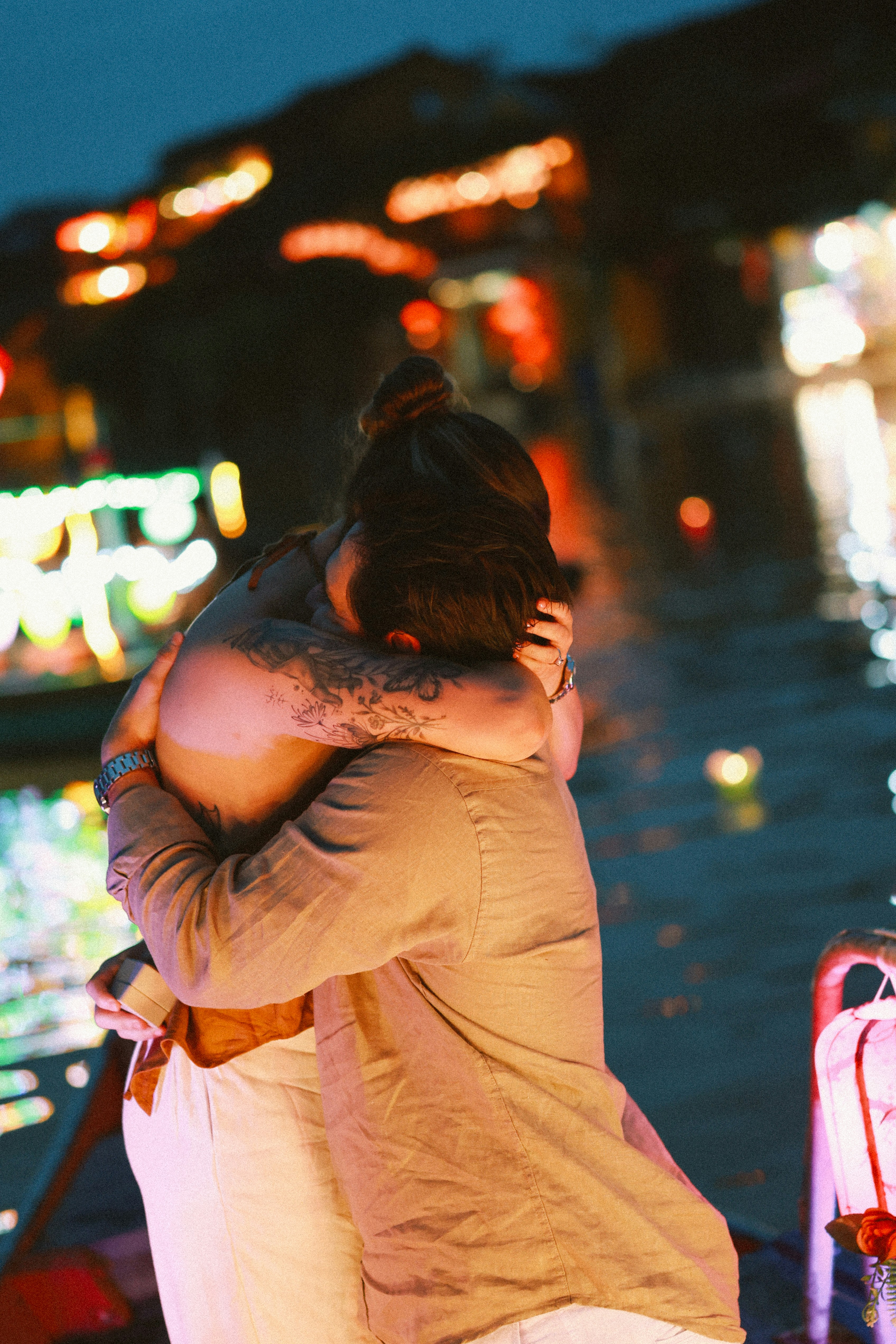 Couple embracing by a water with city lights