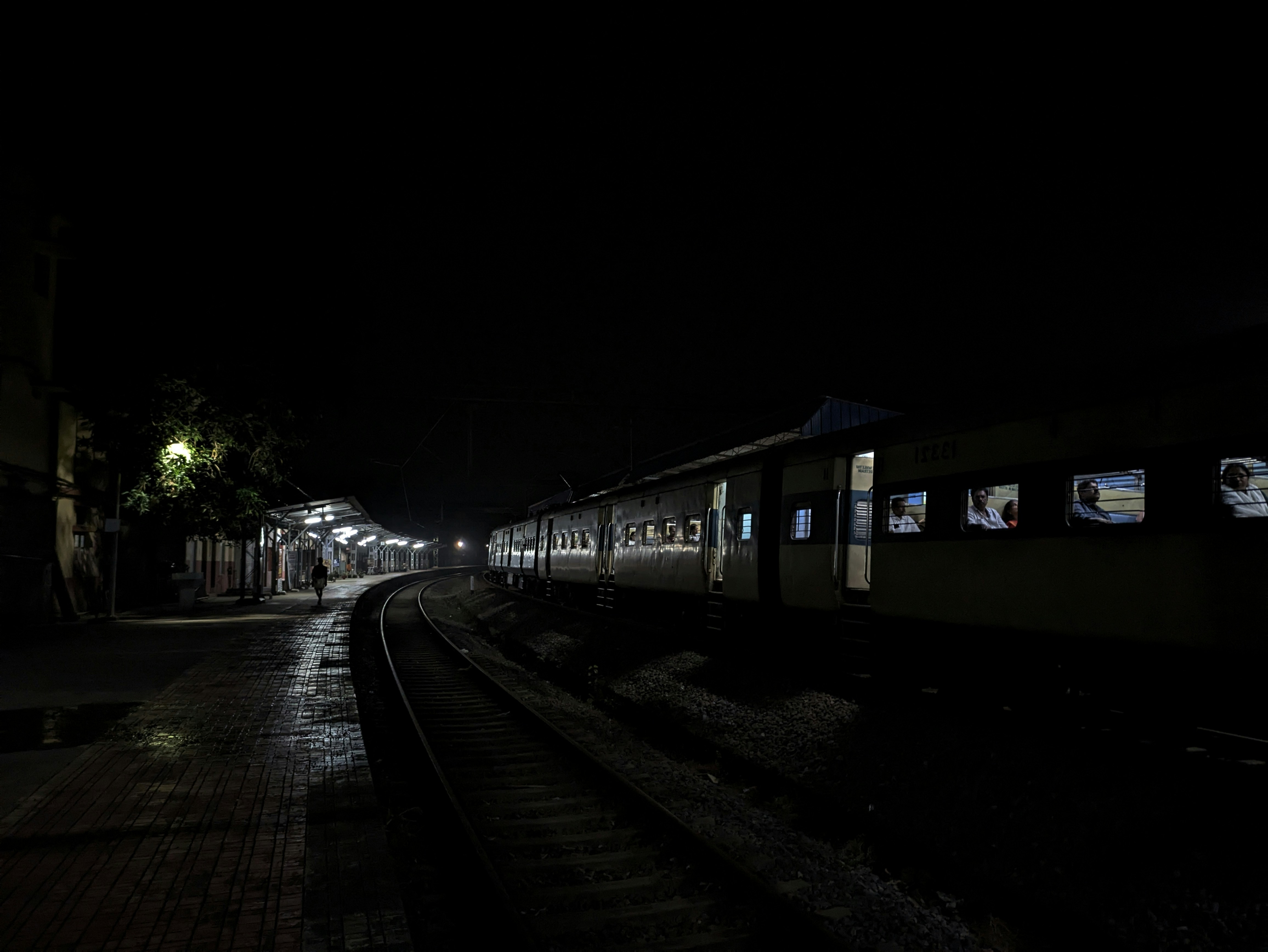 A passenger train at a dark railway station platform at night