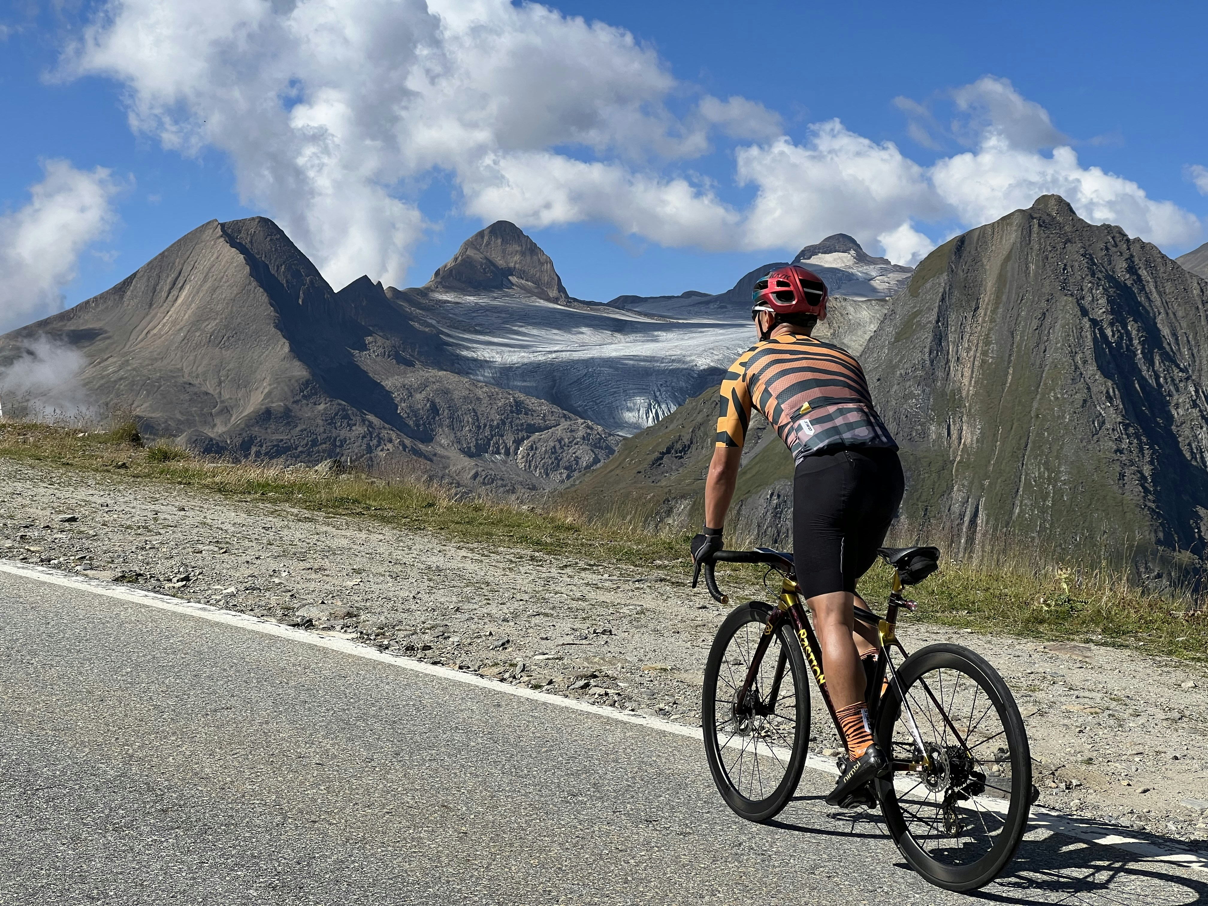 Cyclist on a mountain road with glaciers behind