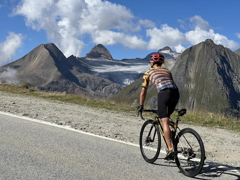 Cyclist climbing a mountain road with peaks in the background