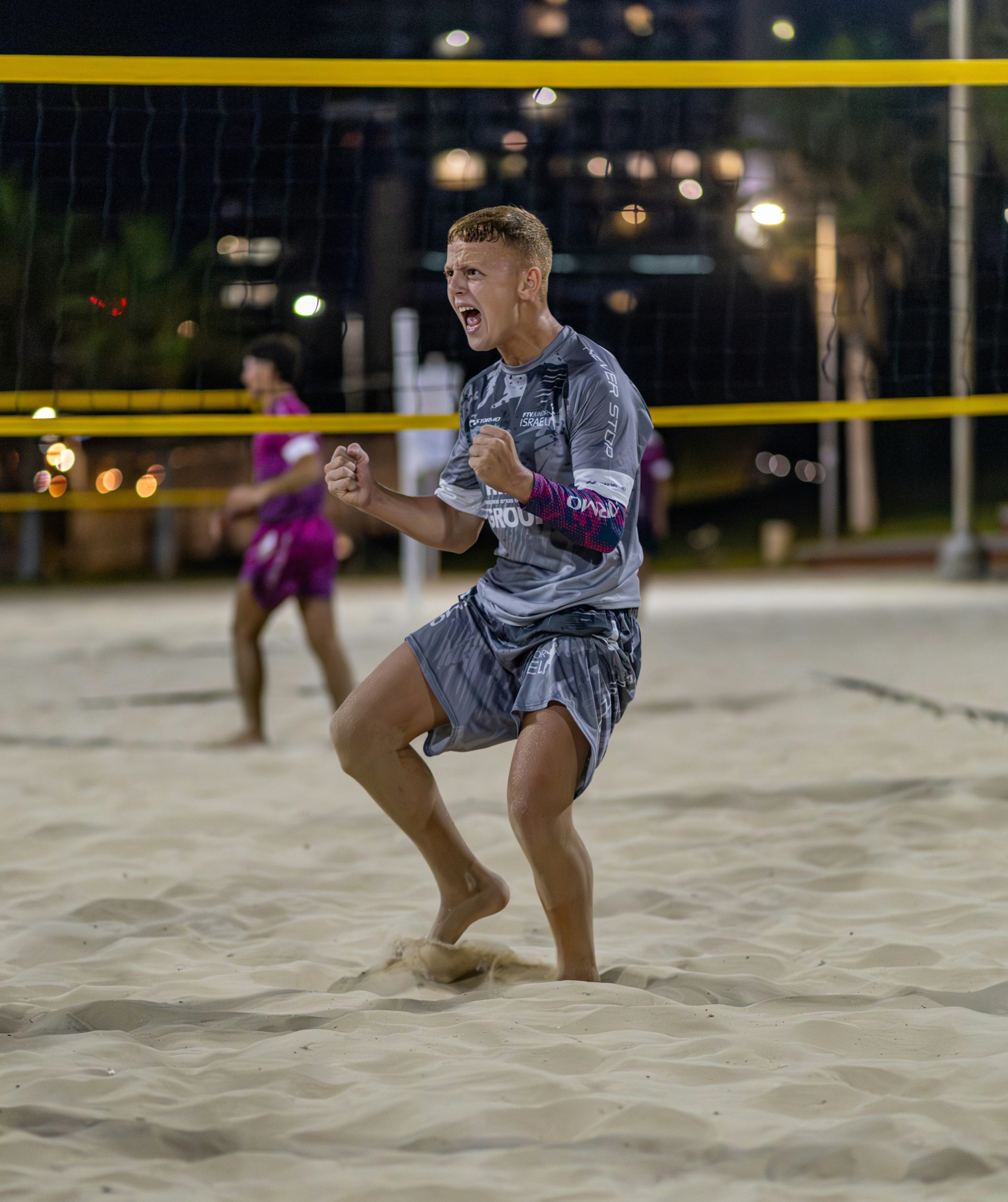 Pemuda merayakan kemenangan di lapangan voli pantai.