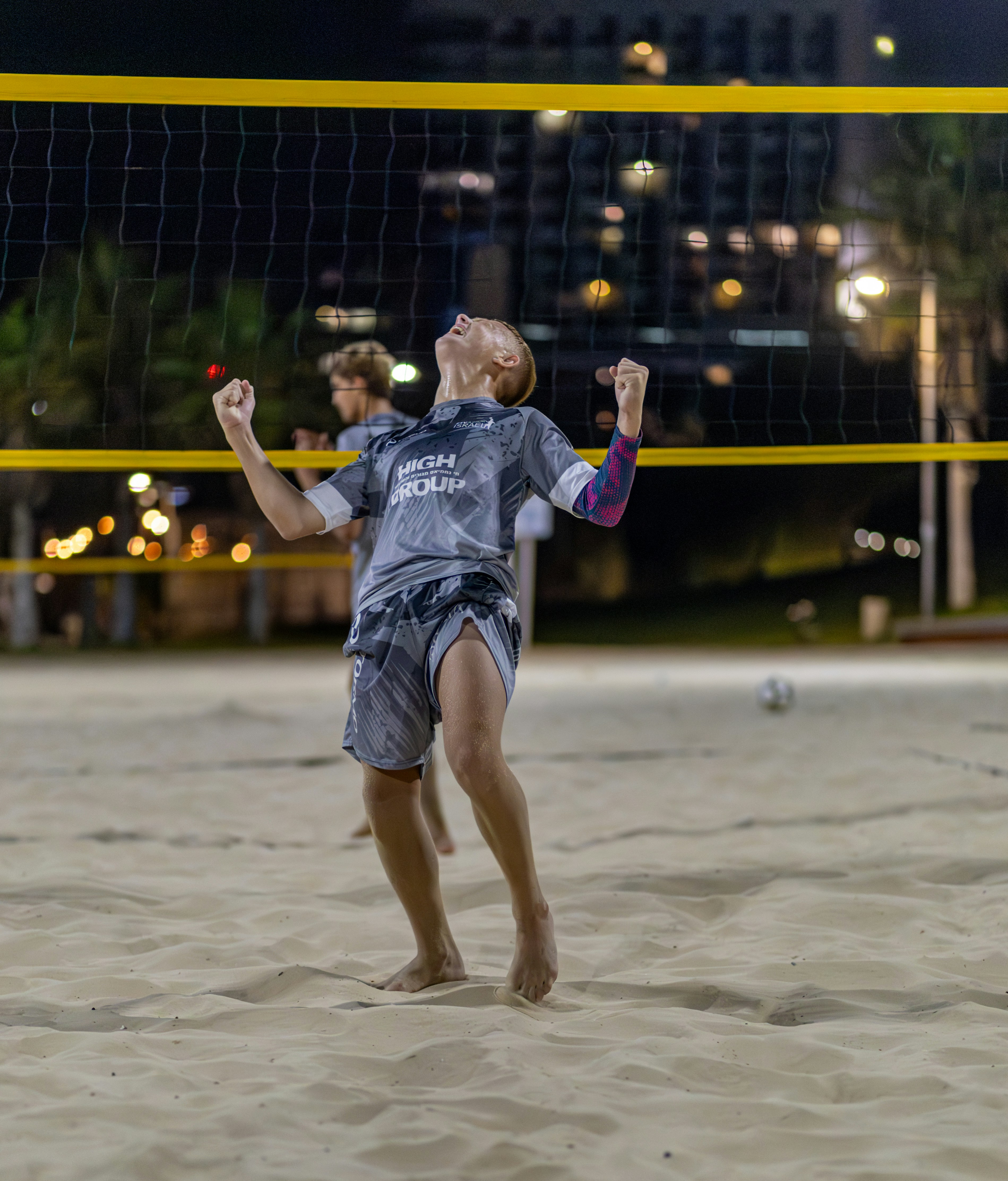 Young man celebrating a win on a beach volleyball court