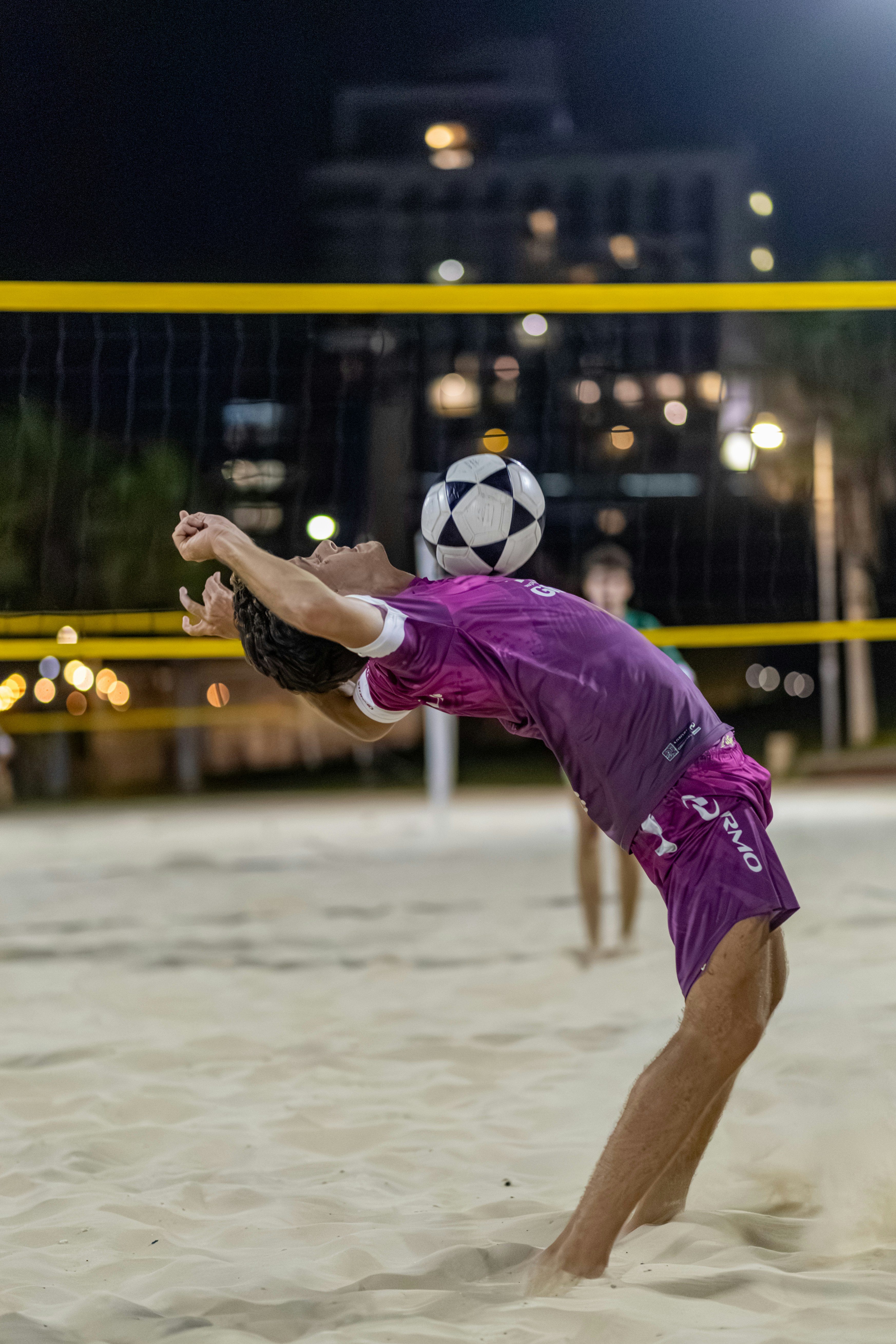 Man balancing soccer ball on head during beach game