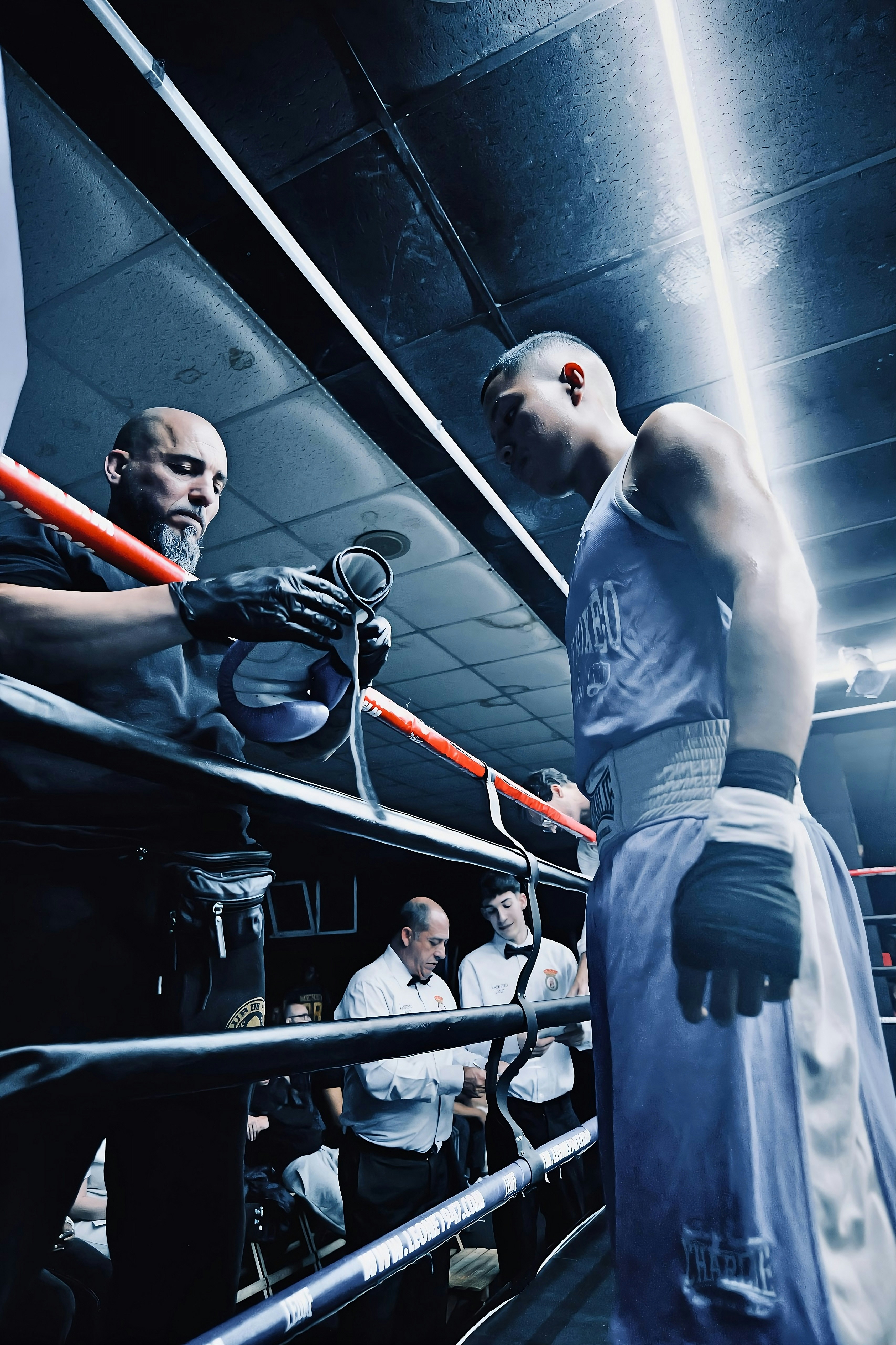 Boxer and trainer in a boxing ring with officials