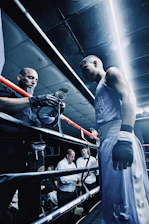 Boxer and trainer in a boxing ring with officials
