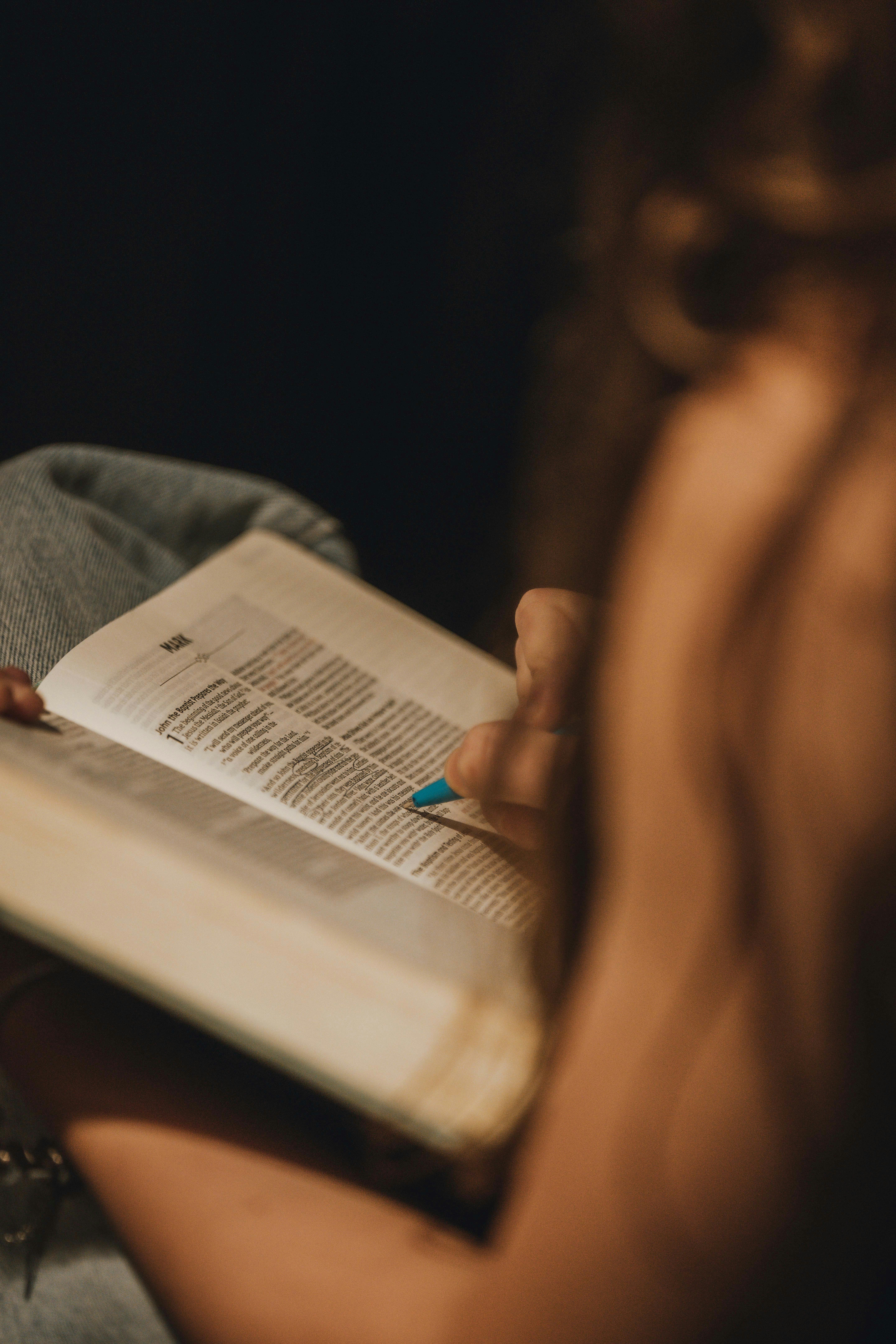 A person reading a book with a blue fingernail.