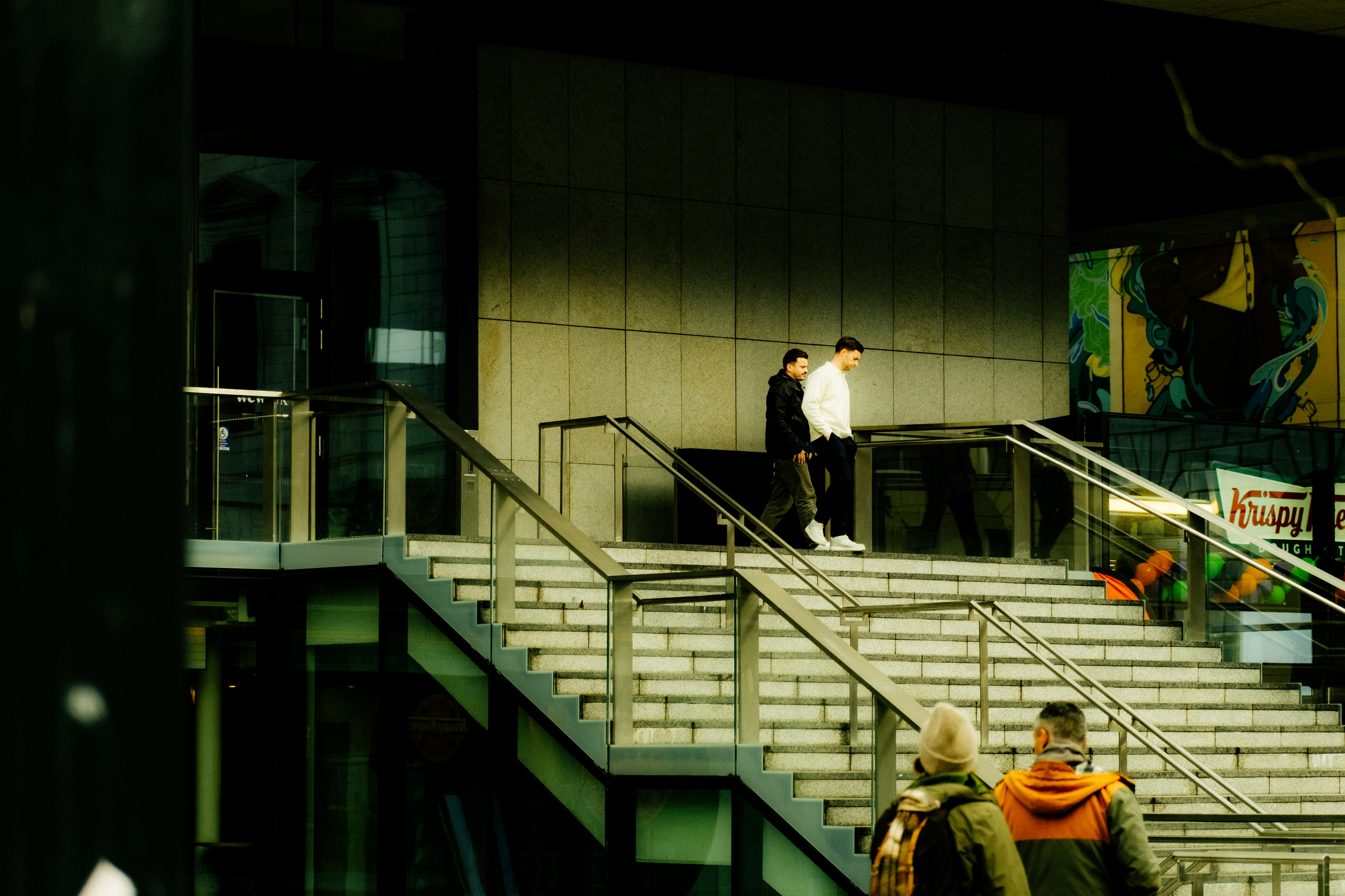 Two people ascend outdoor stairs near a building.
