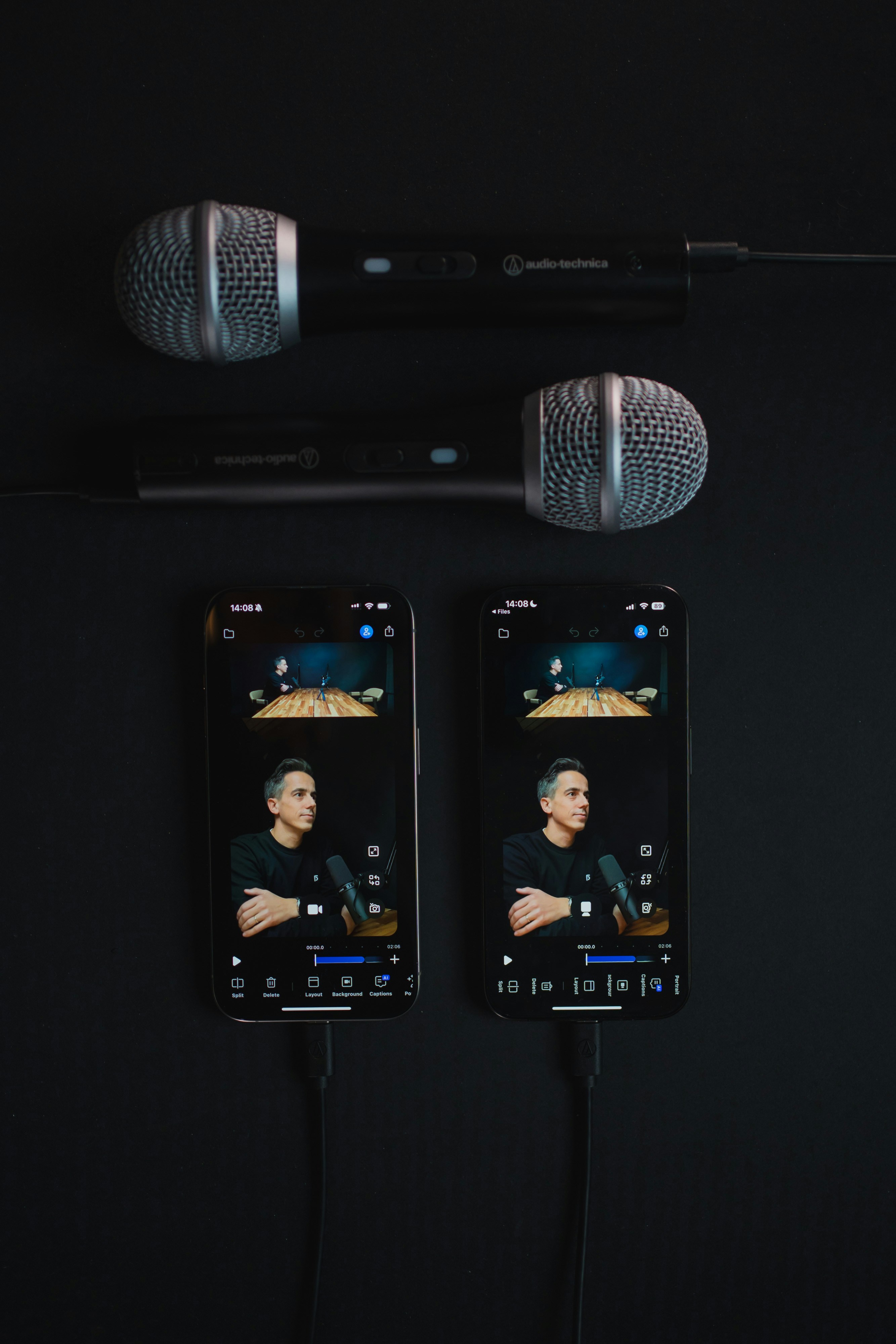Two smartphones and professional microphones arranged on a wooden table.