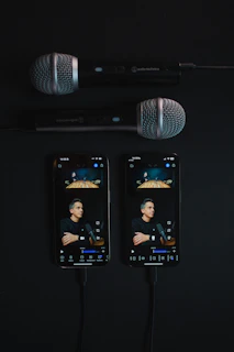 Two phones connected to microphones on black surface