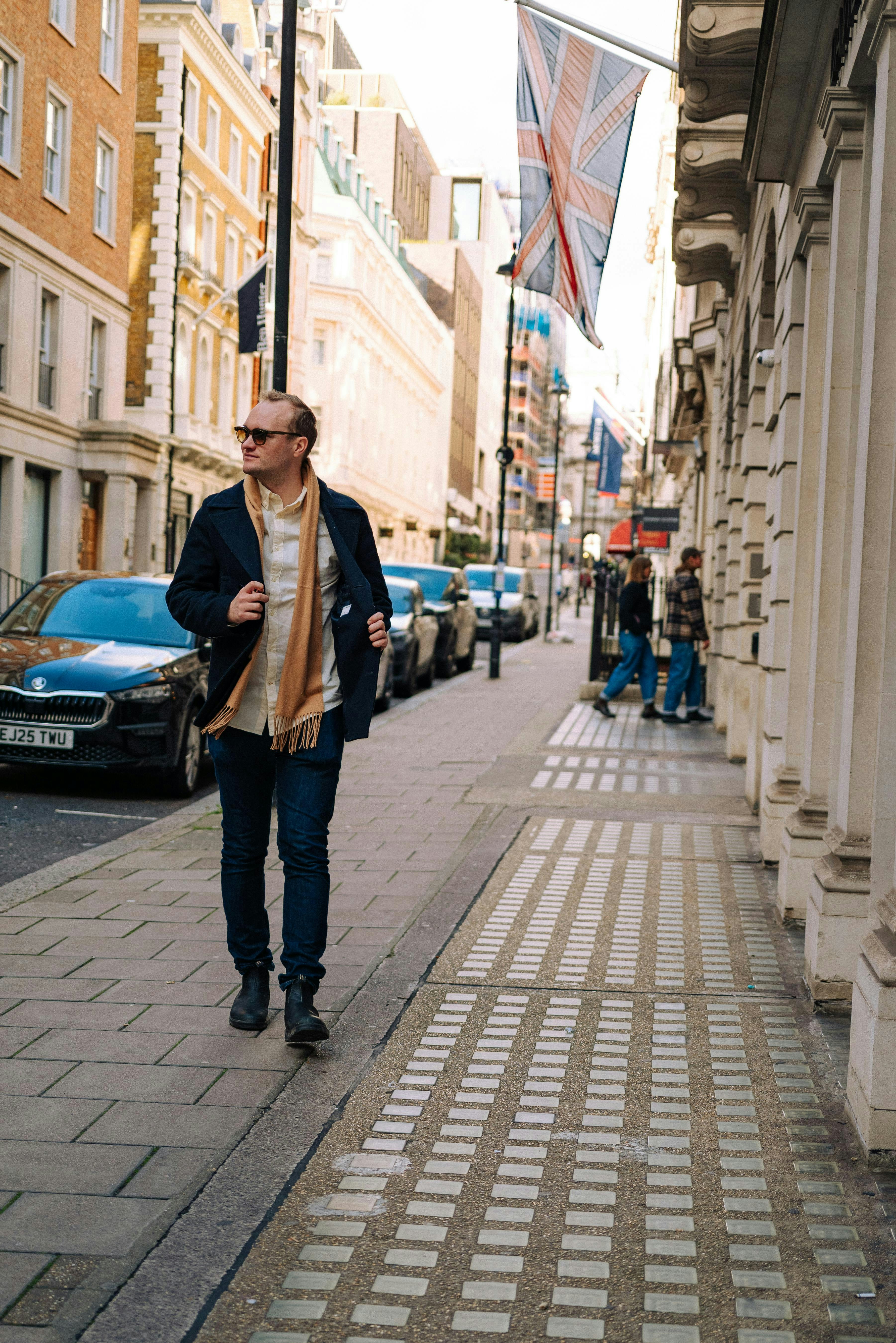 Hombre caminando por la calle de la ciudad con la bandera de la Union Jack.
