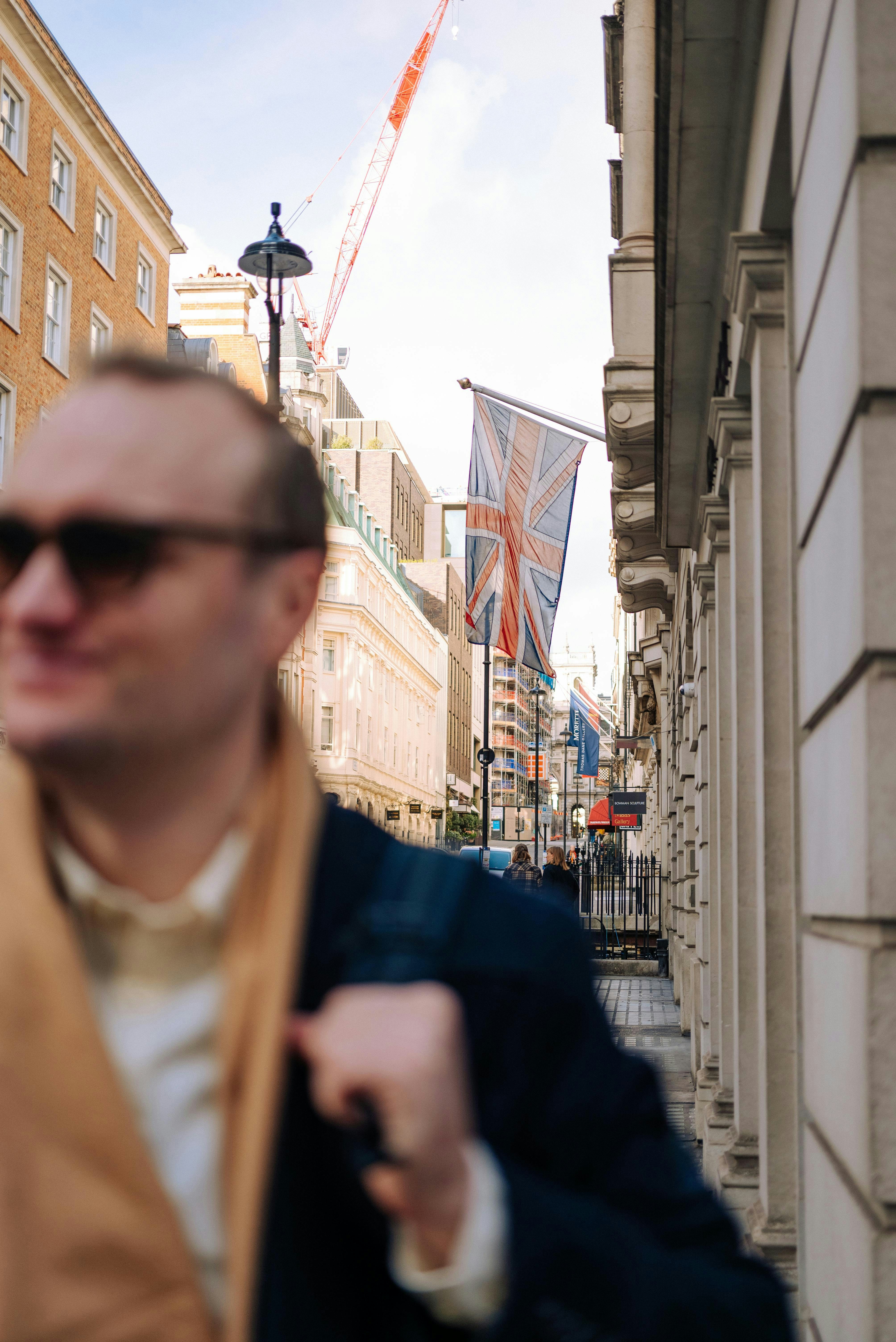 Man walking on street with union jack flags.