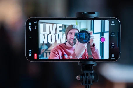 Man filming himself with a smartphone on a tripod.