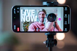 Man filming with camera on phone screen live now