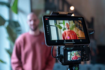 Man filming himself with a camera and tablet.