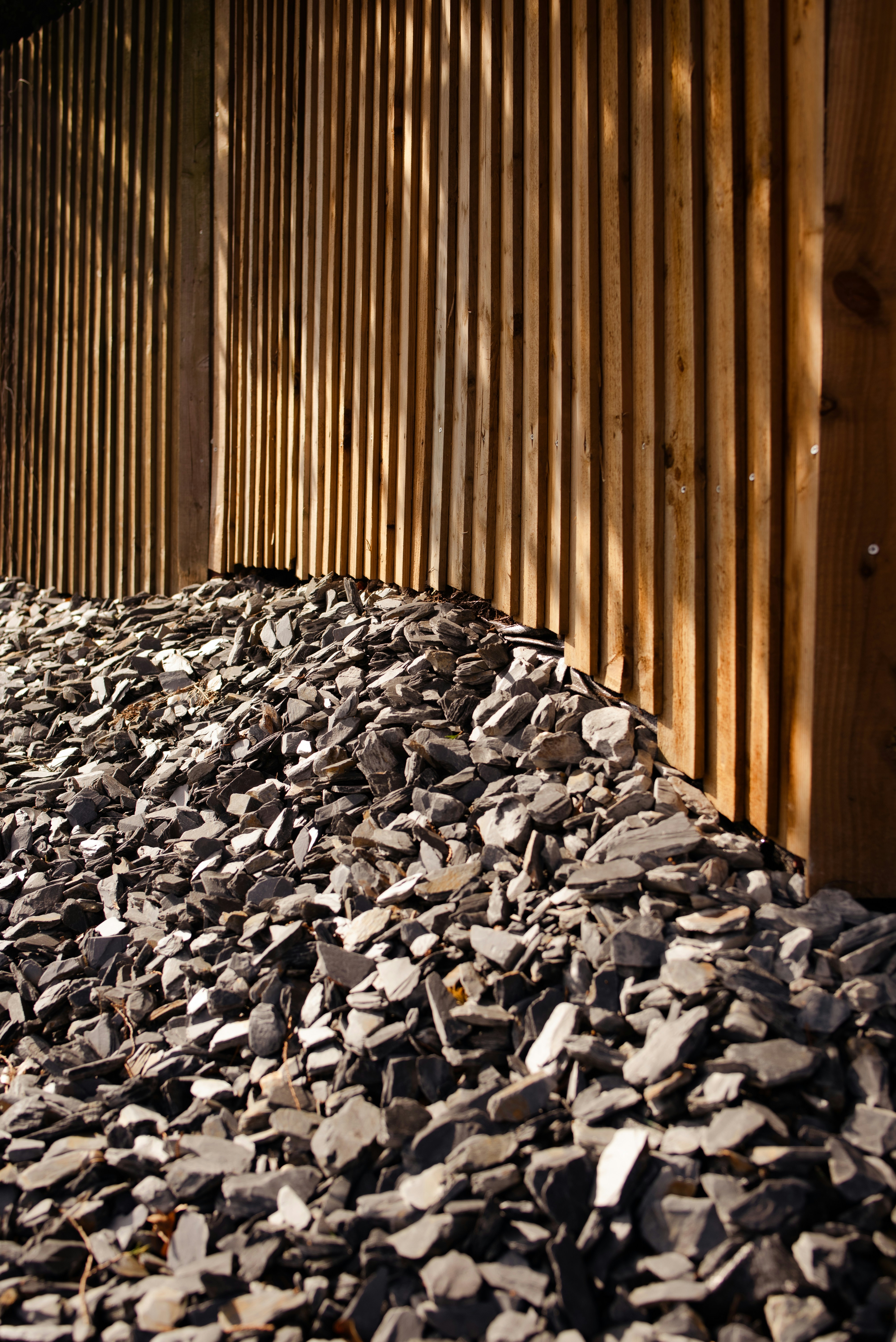 Un mucchio di pietre grigie contro una recinzione di legno