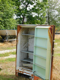 Old rusty refrigerator standing outdoors in grass