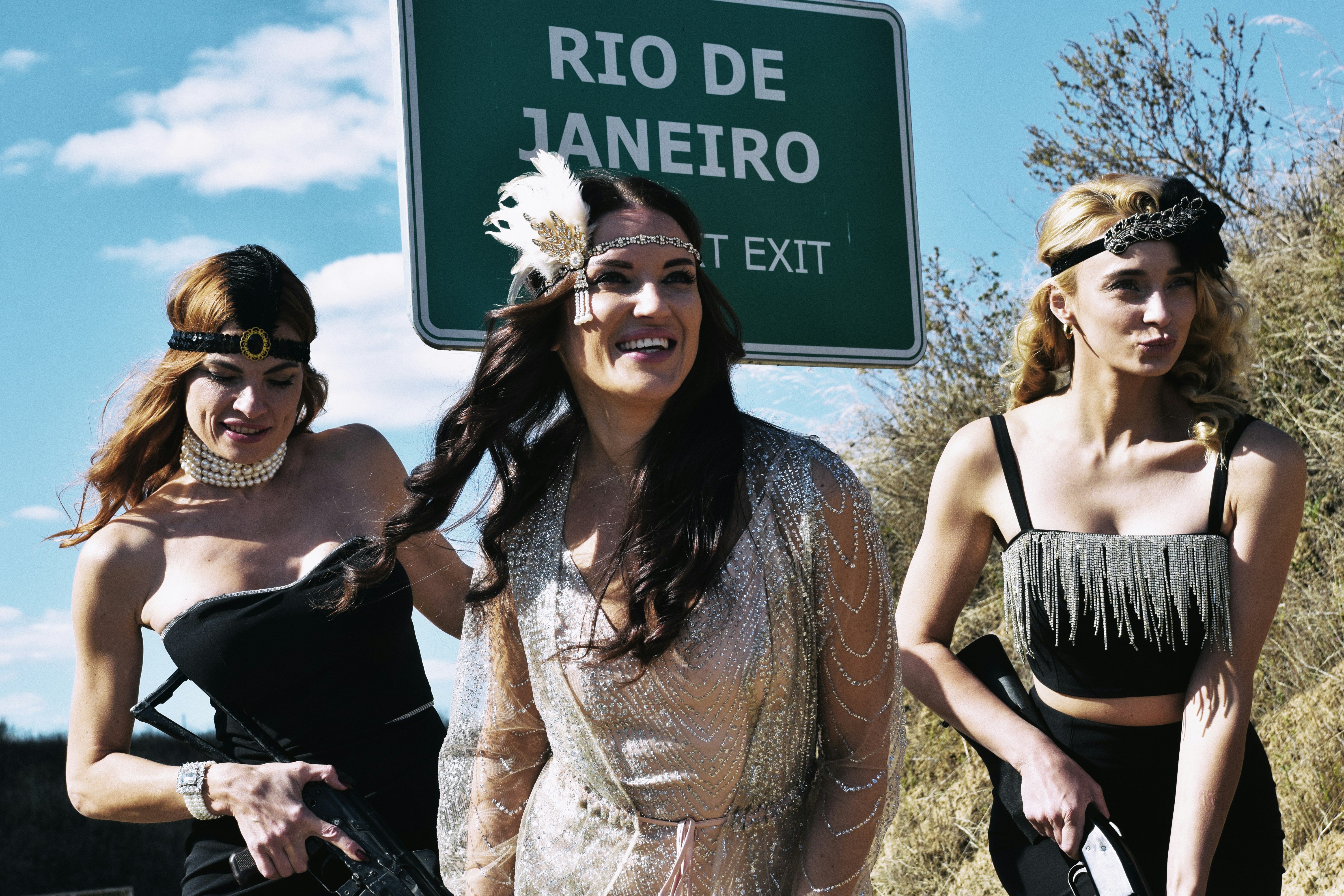 Three women in vintage attire near rio de janeiro sign.