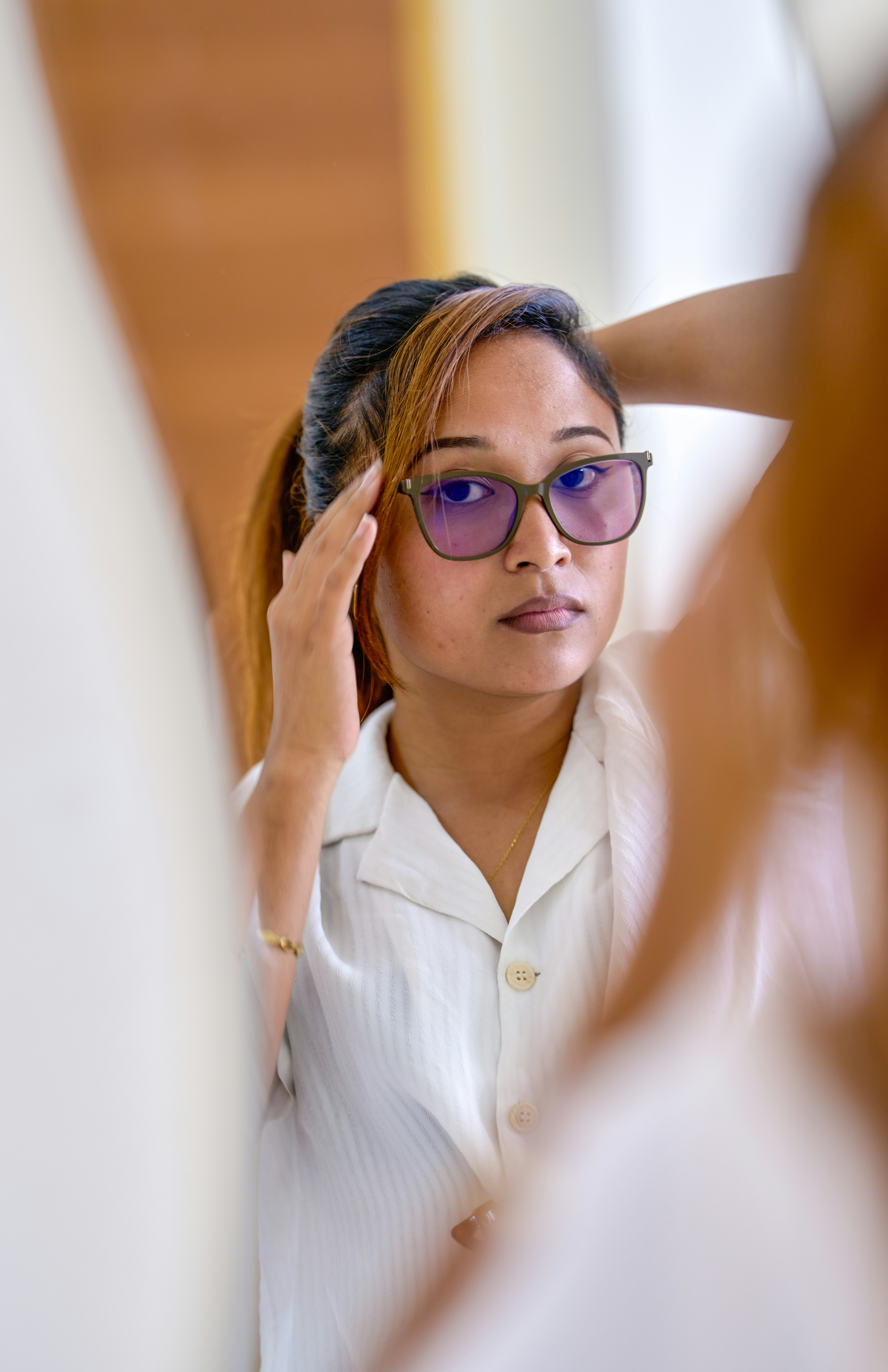 Mulher ajeitando cabelo enquanto se olha no espelho