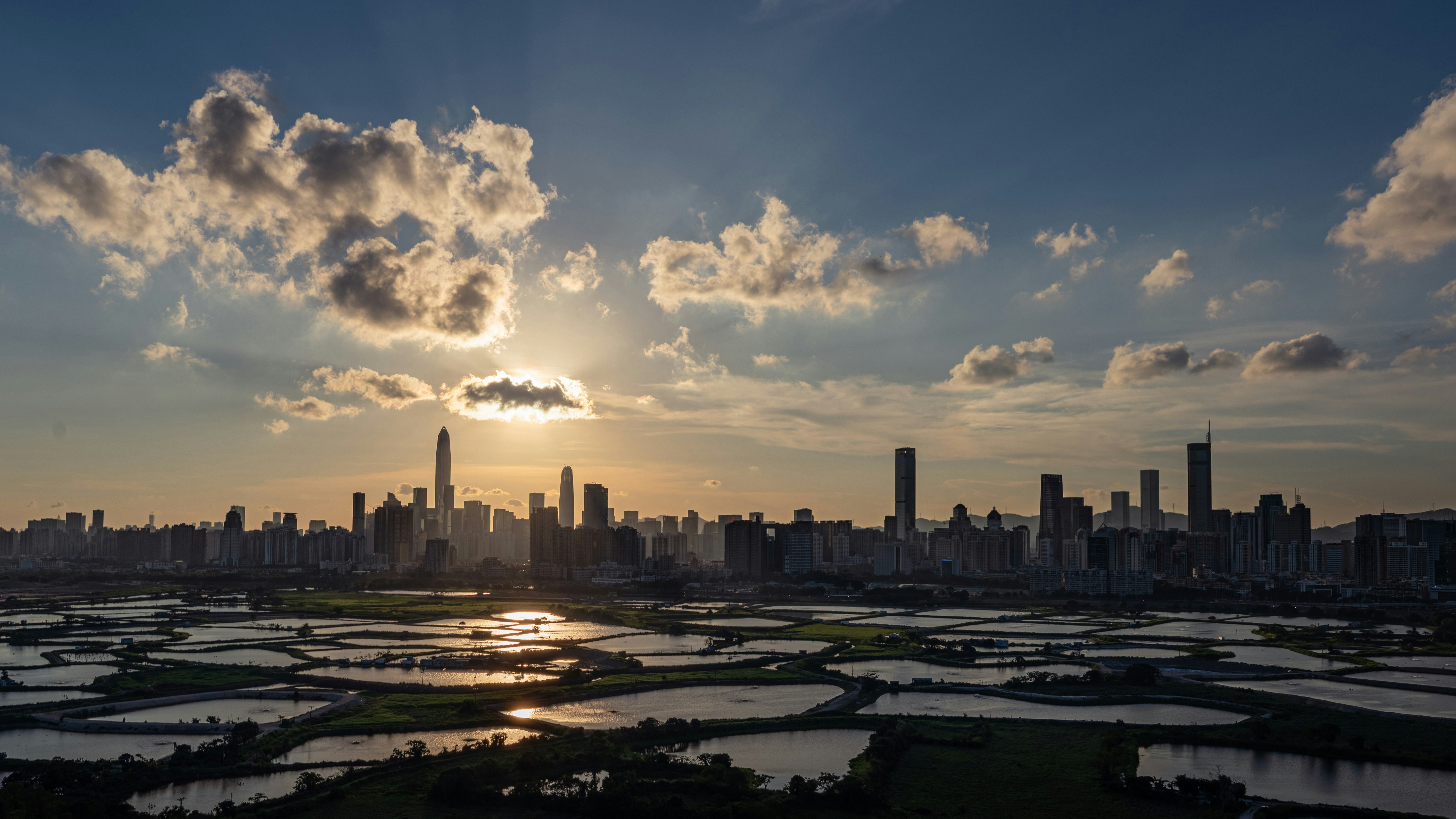 City skyline at sunset with reflective water fields.