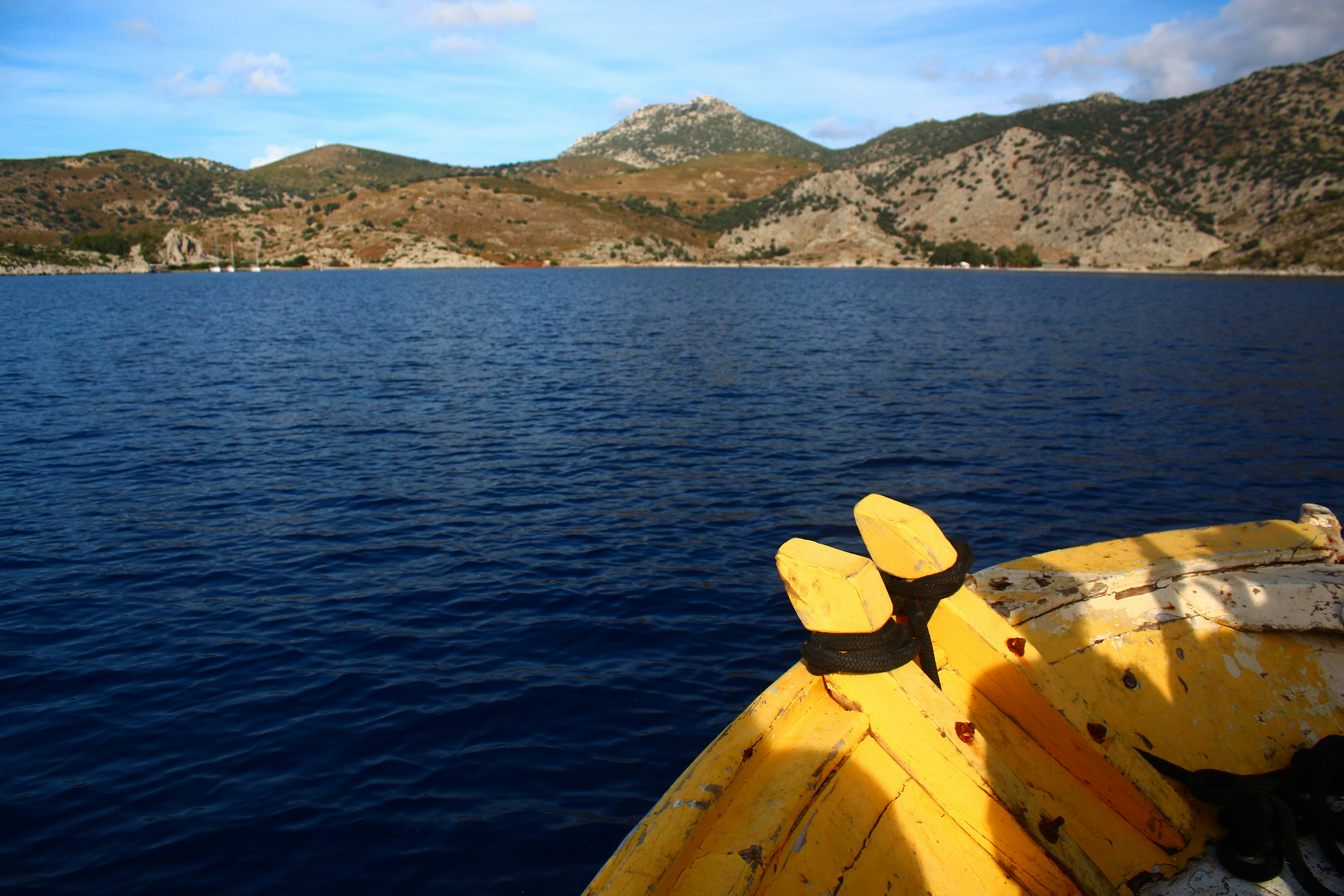 Boat prow on deep blue water with distant mountains.
