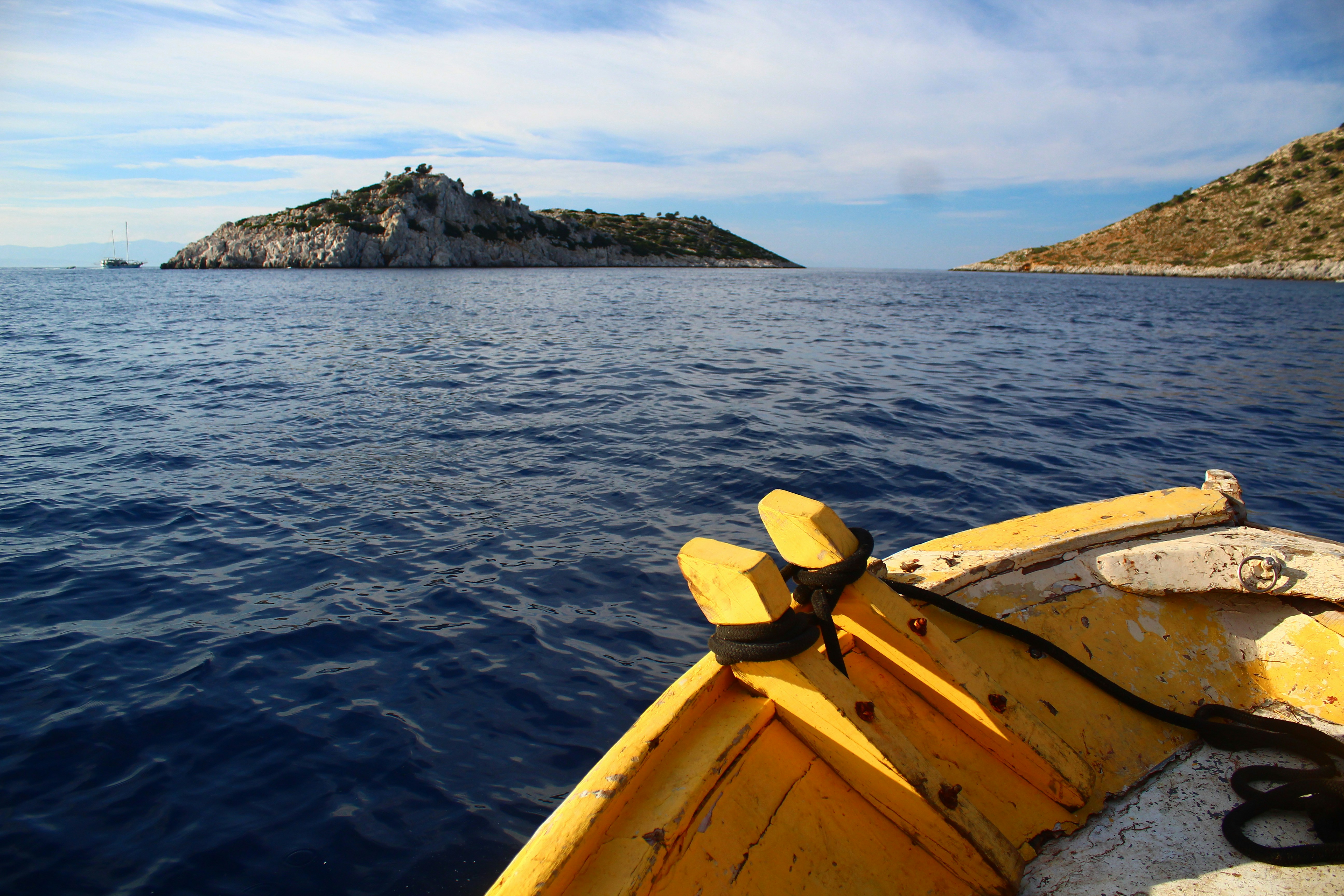 Yellow boat sailing towards a rocky island.