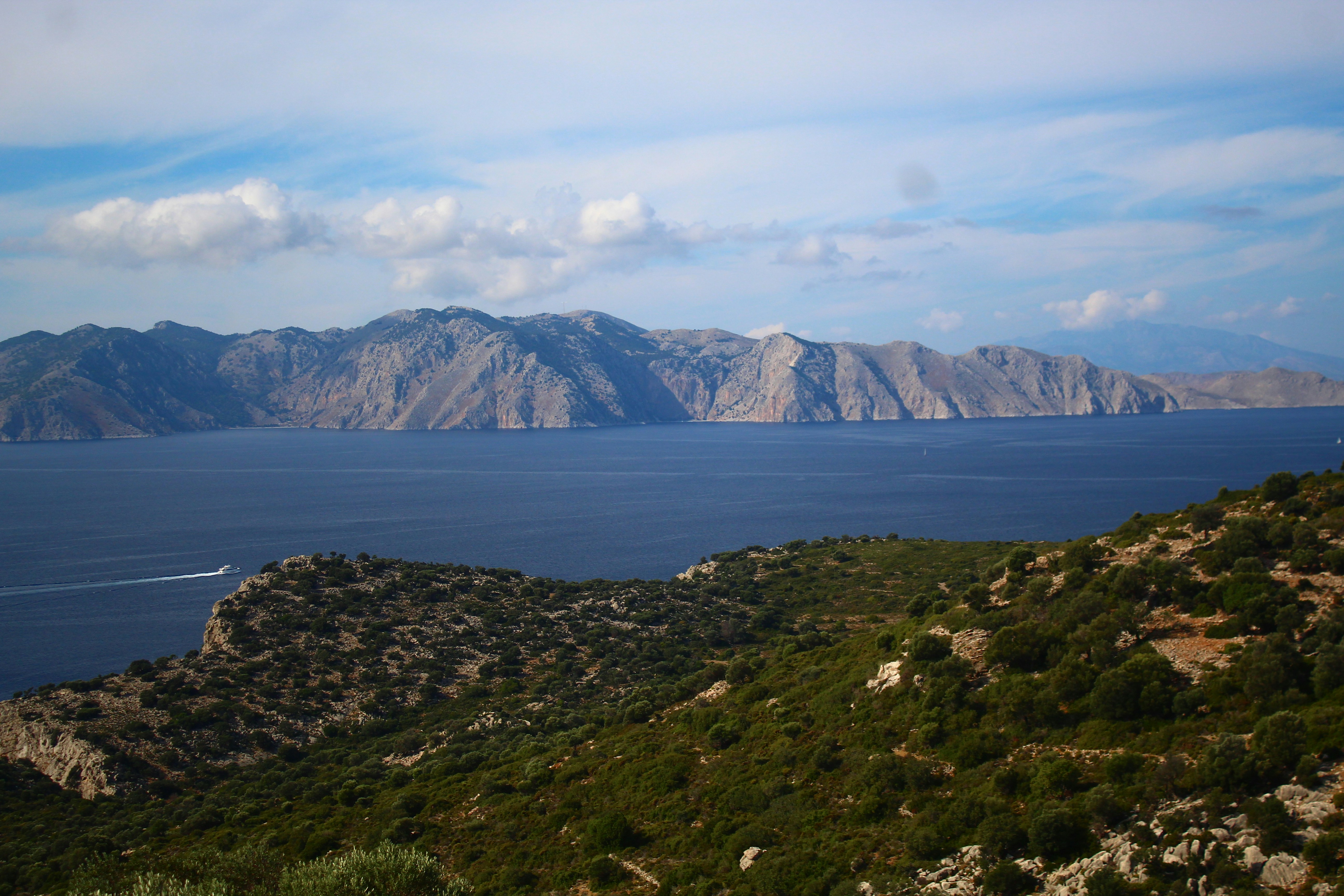 Coastal mountains rise above a calm blue sea.