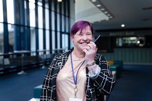 Woman with purple hair smiling and holding a device.
