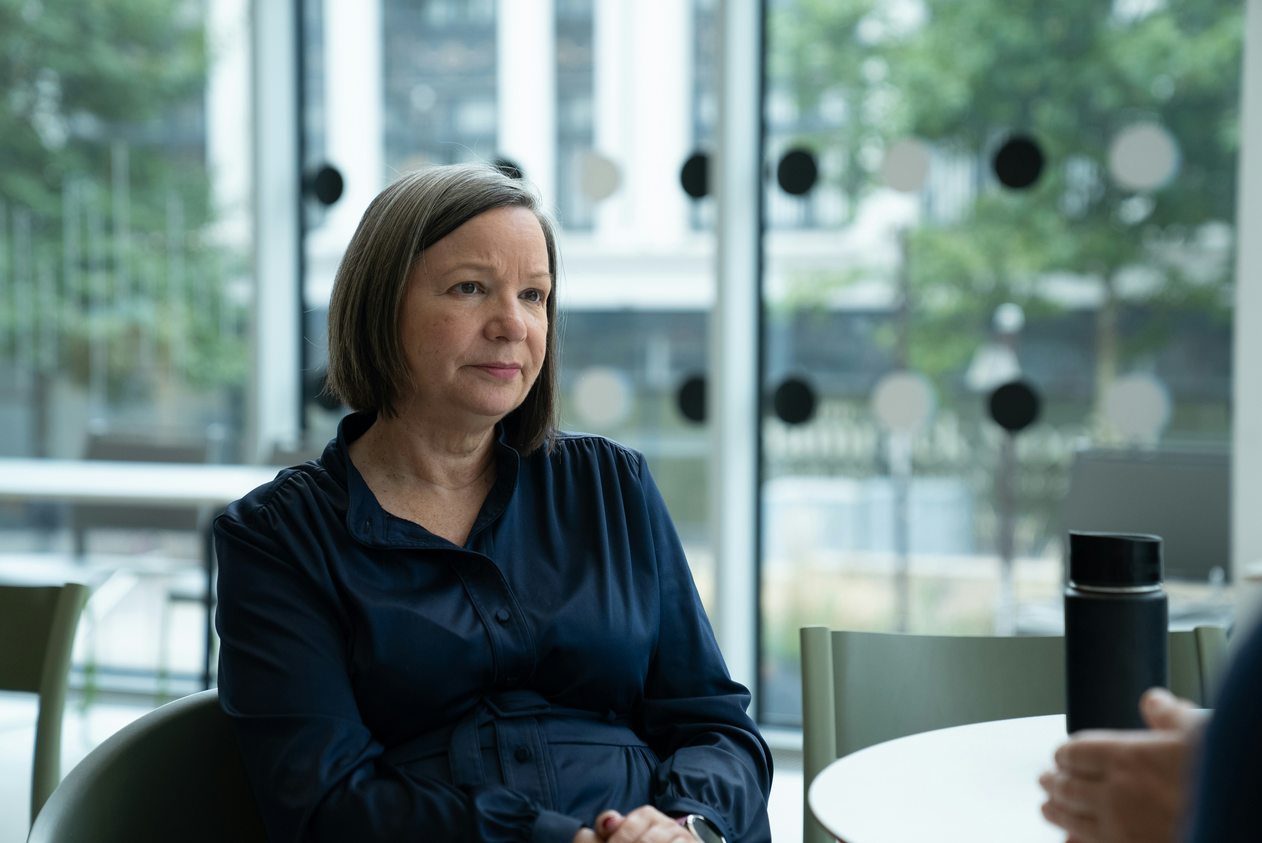 A woman sits at a table in a modern building.