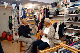 Two women talking in a cluttered shop.