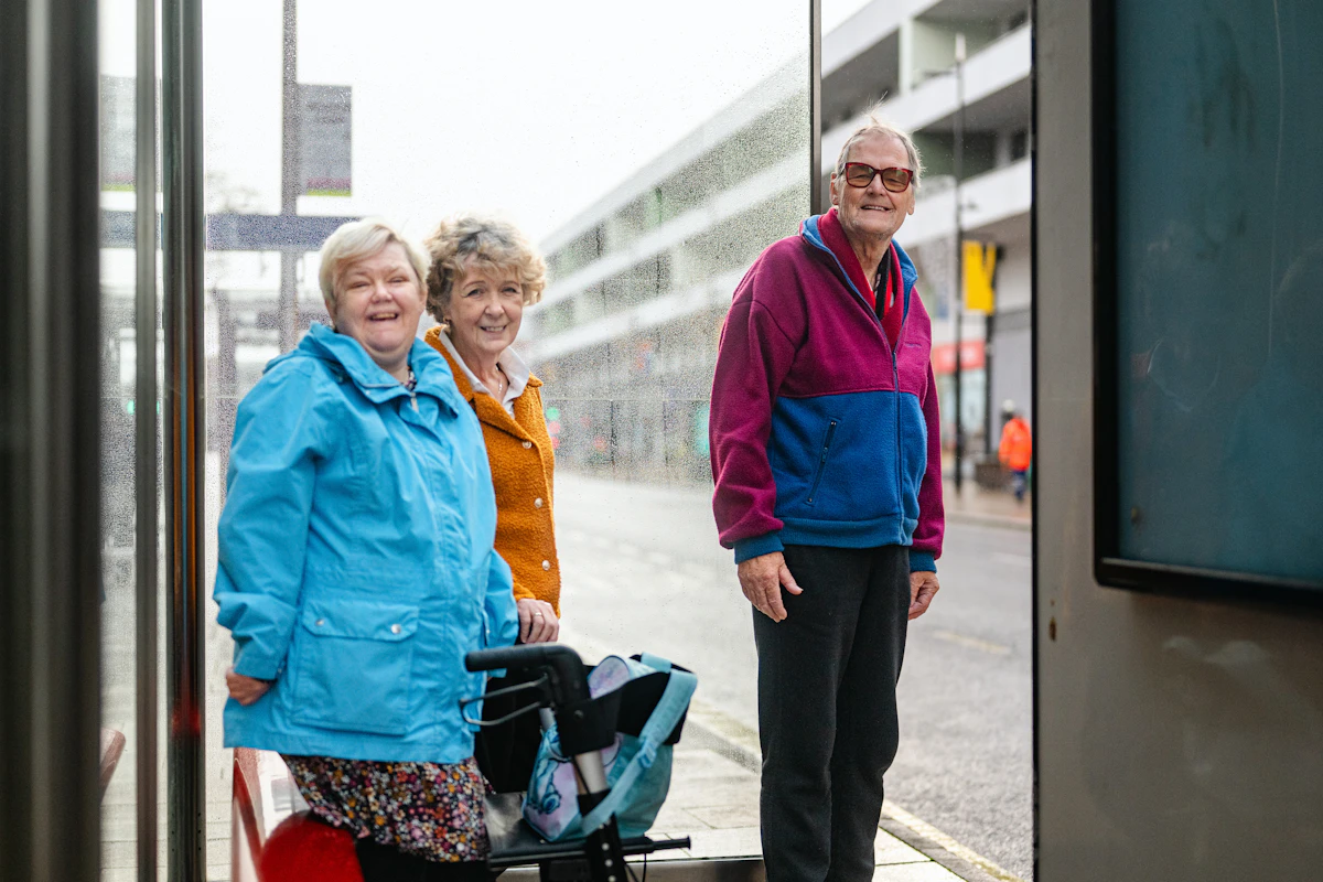 Three older friends chatting at a neighborhood bus stop