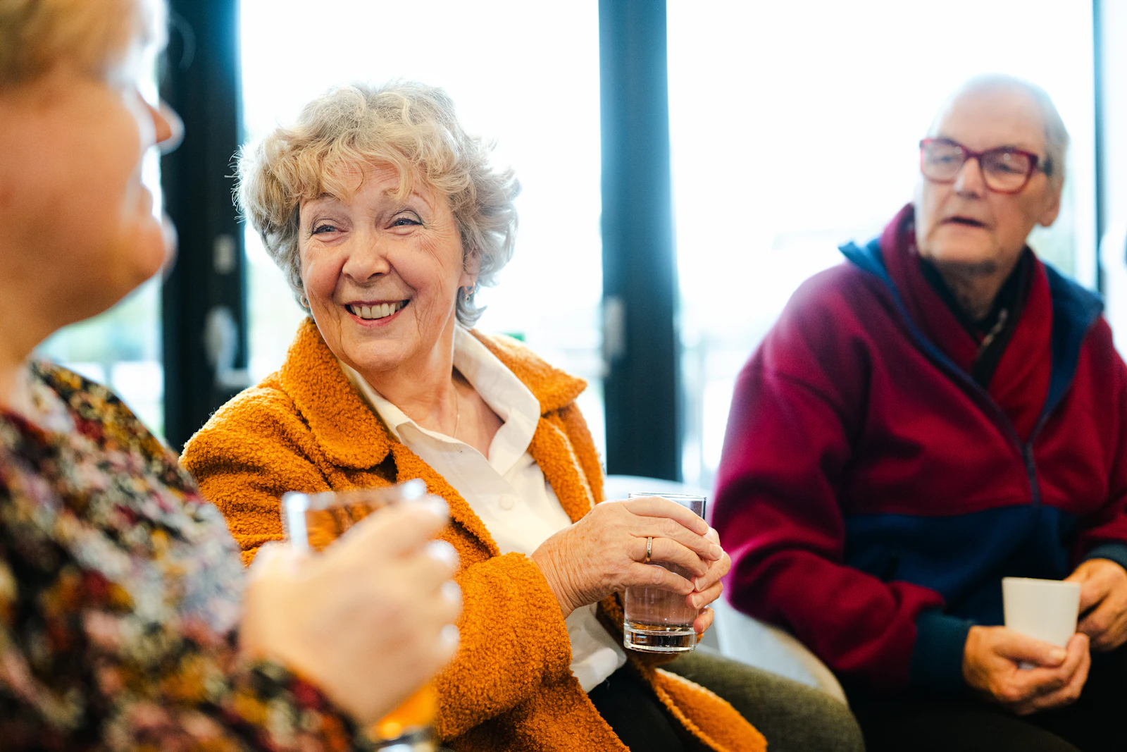 Three older adults talking and smiling warmly together, representing the supportive conversations that often come before a first respite call