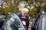 Elderly man getting into a car