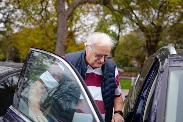 An older man being helped into a car for an appointment