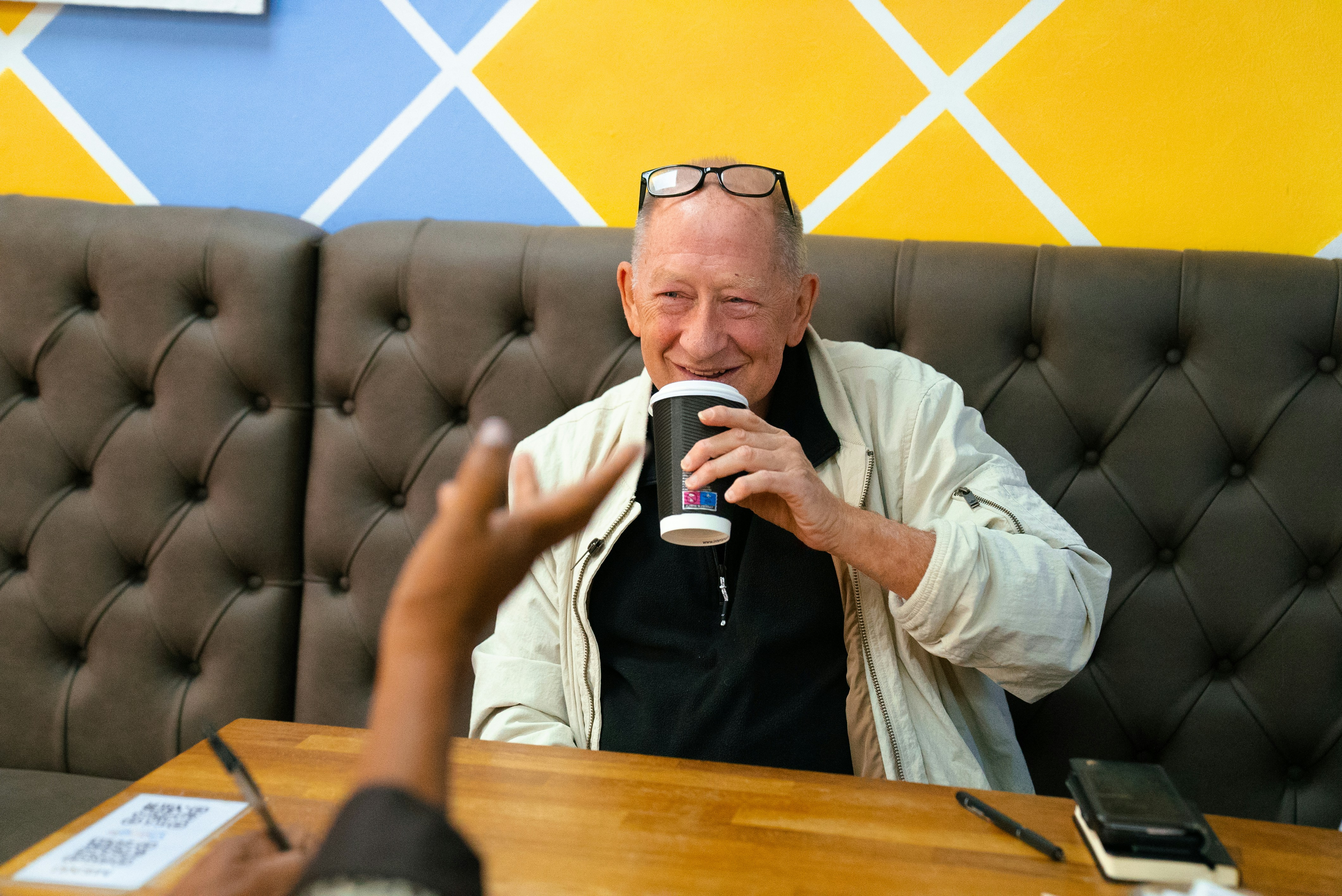 Elderly man drinking from a cup at a table