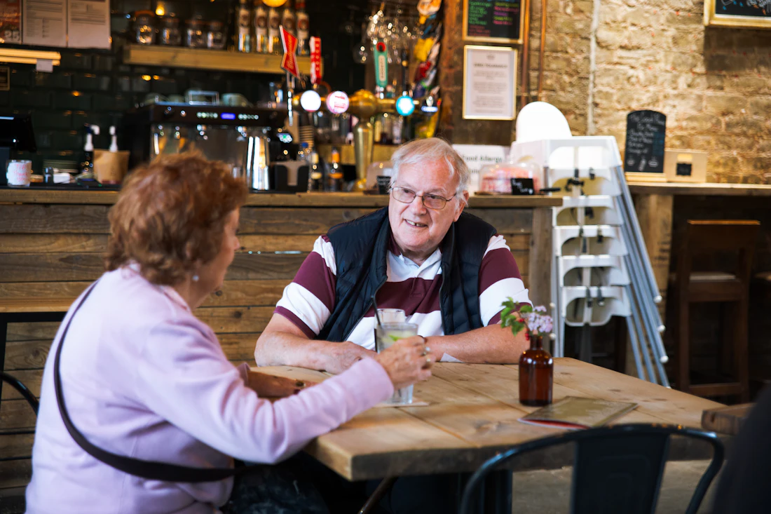 An older couple sitting and talking at a table, the kind of visit when families often first sense a problem