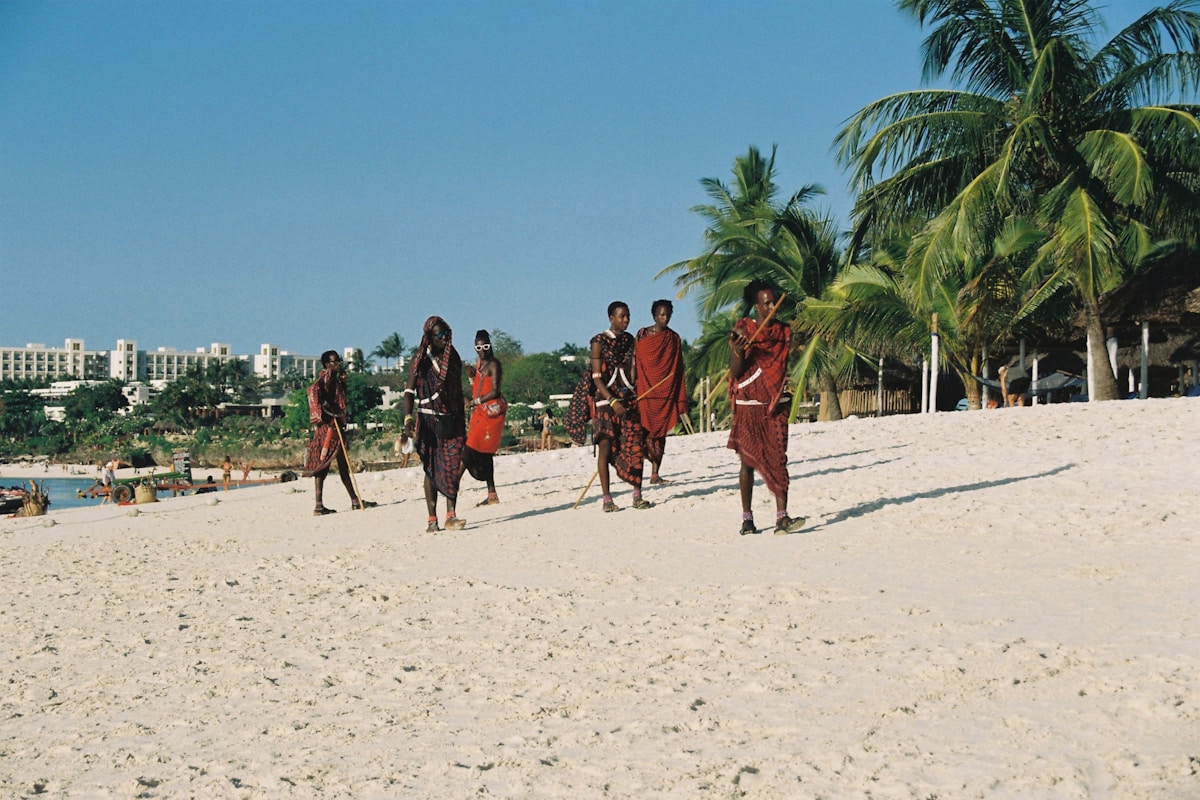 People in traditional clothing walking on a sandy beach