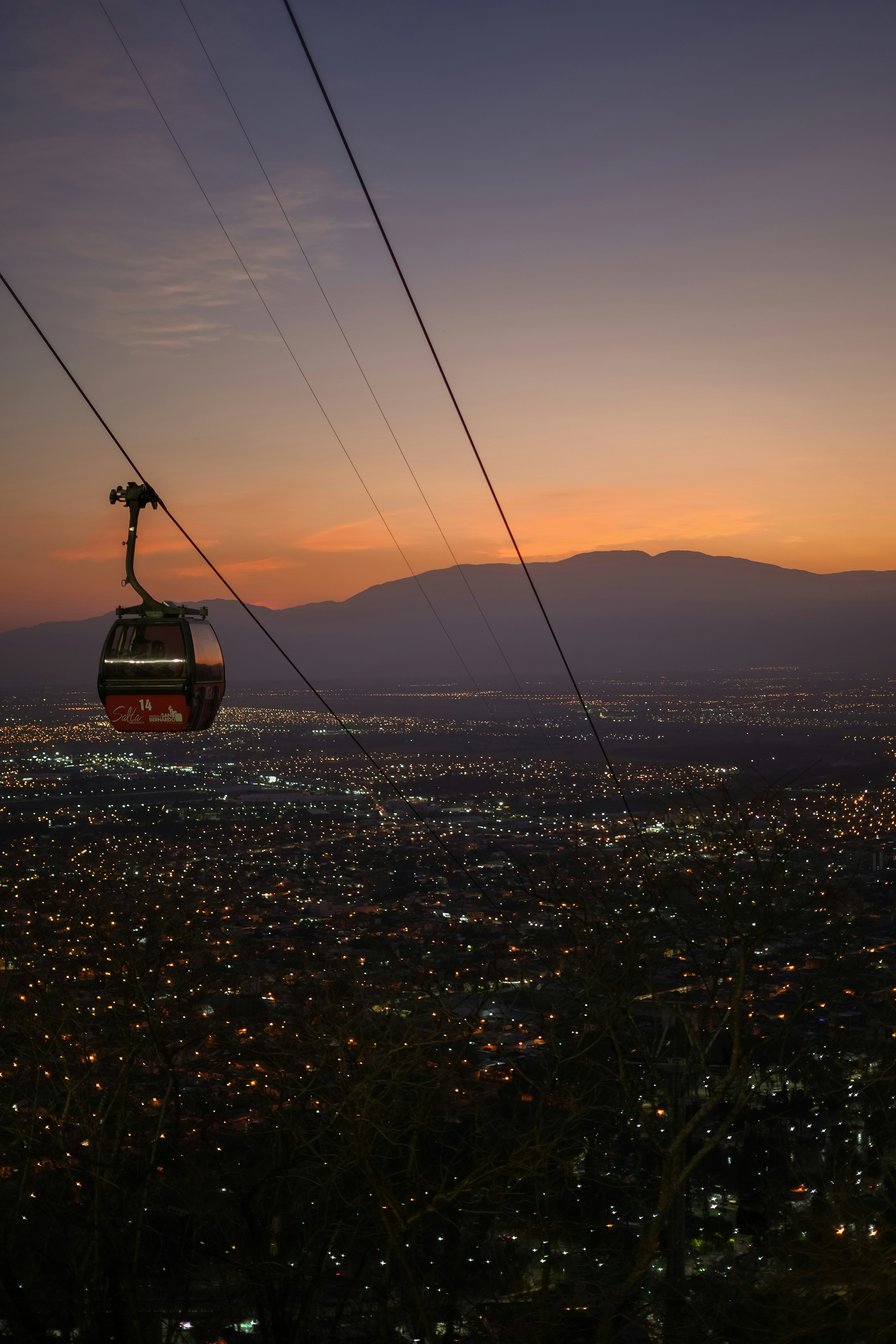 Cable car over city lights at sunset