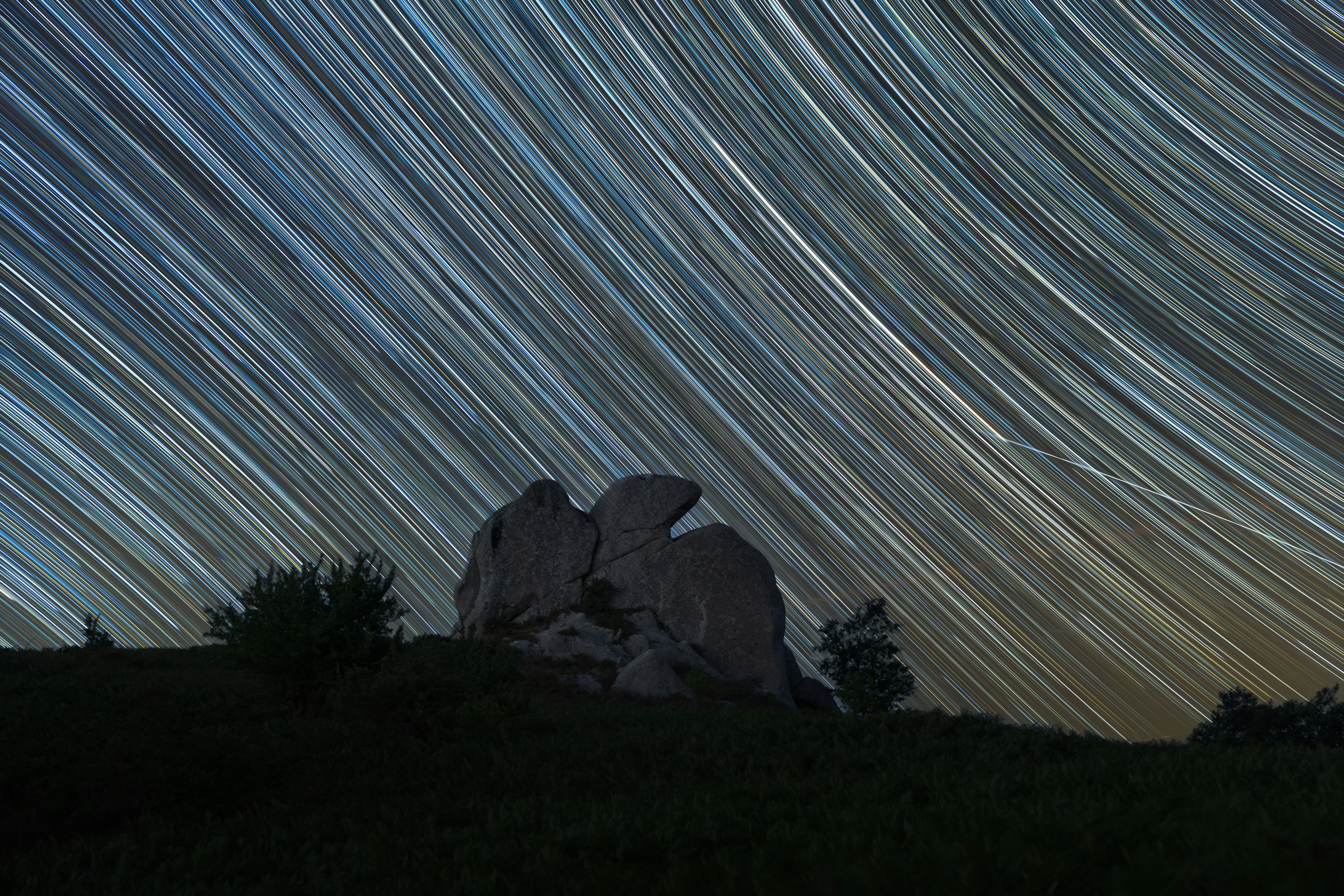 Star trails over rocky hills at night
