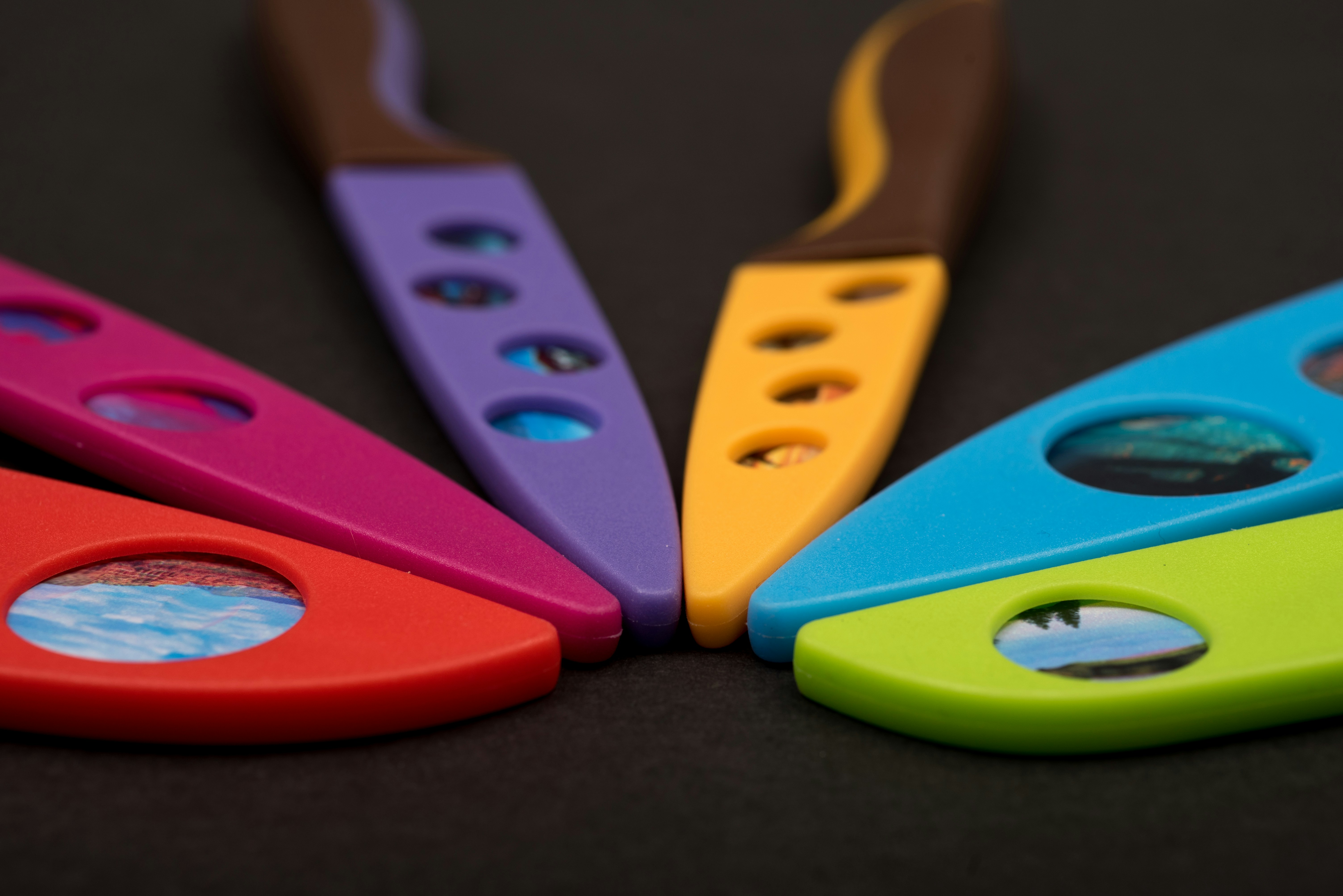 Colorful knives with scenic inserts arranged in a circle.