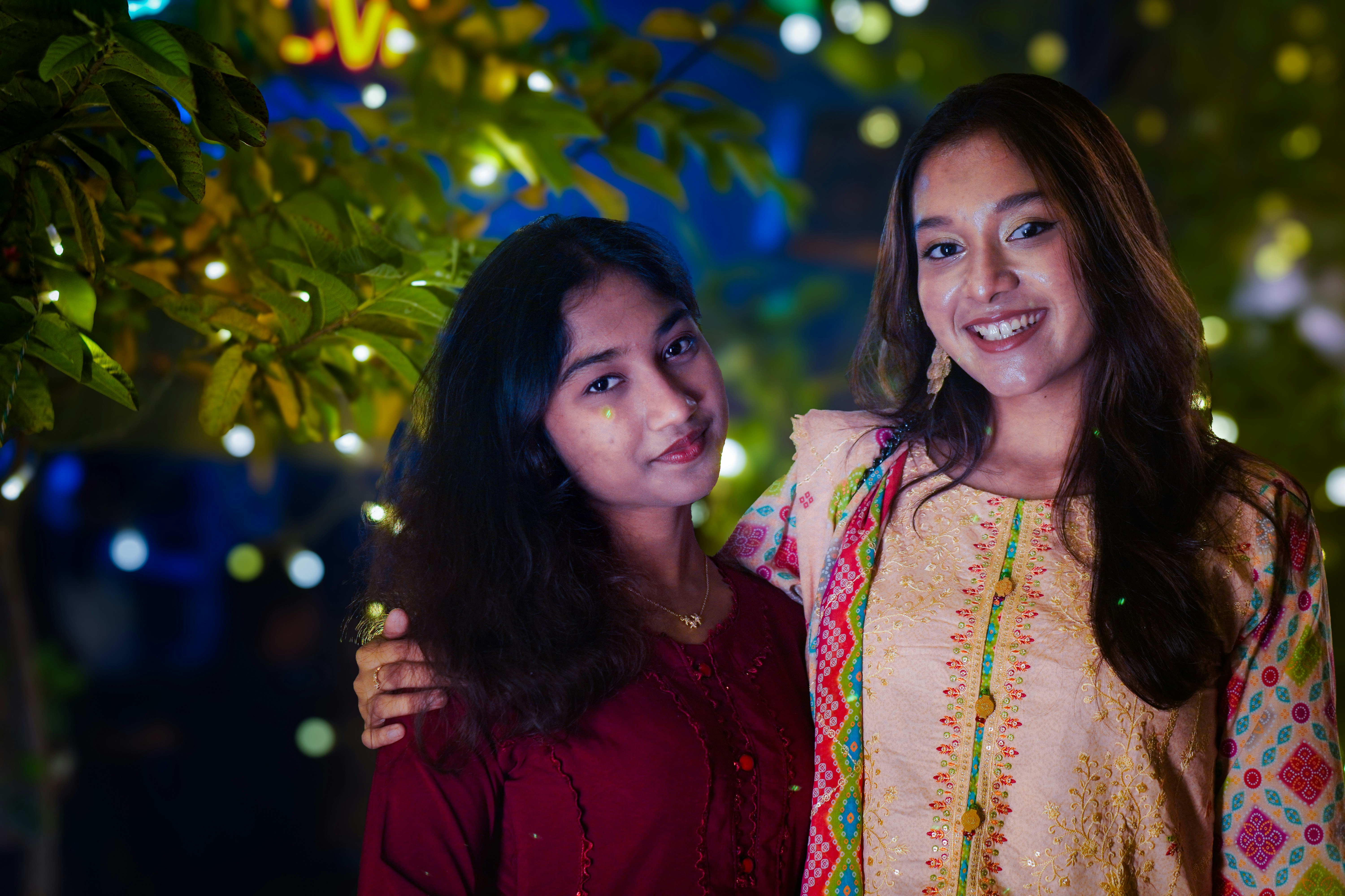 Two young women smiling with blurred festive lights