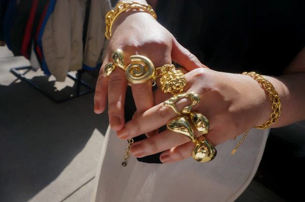 Hands wearing stacked gold jewellery