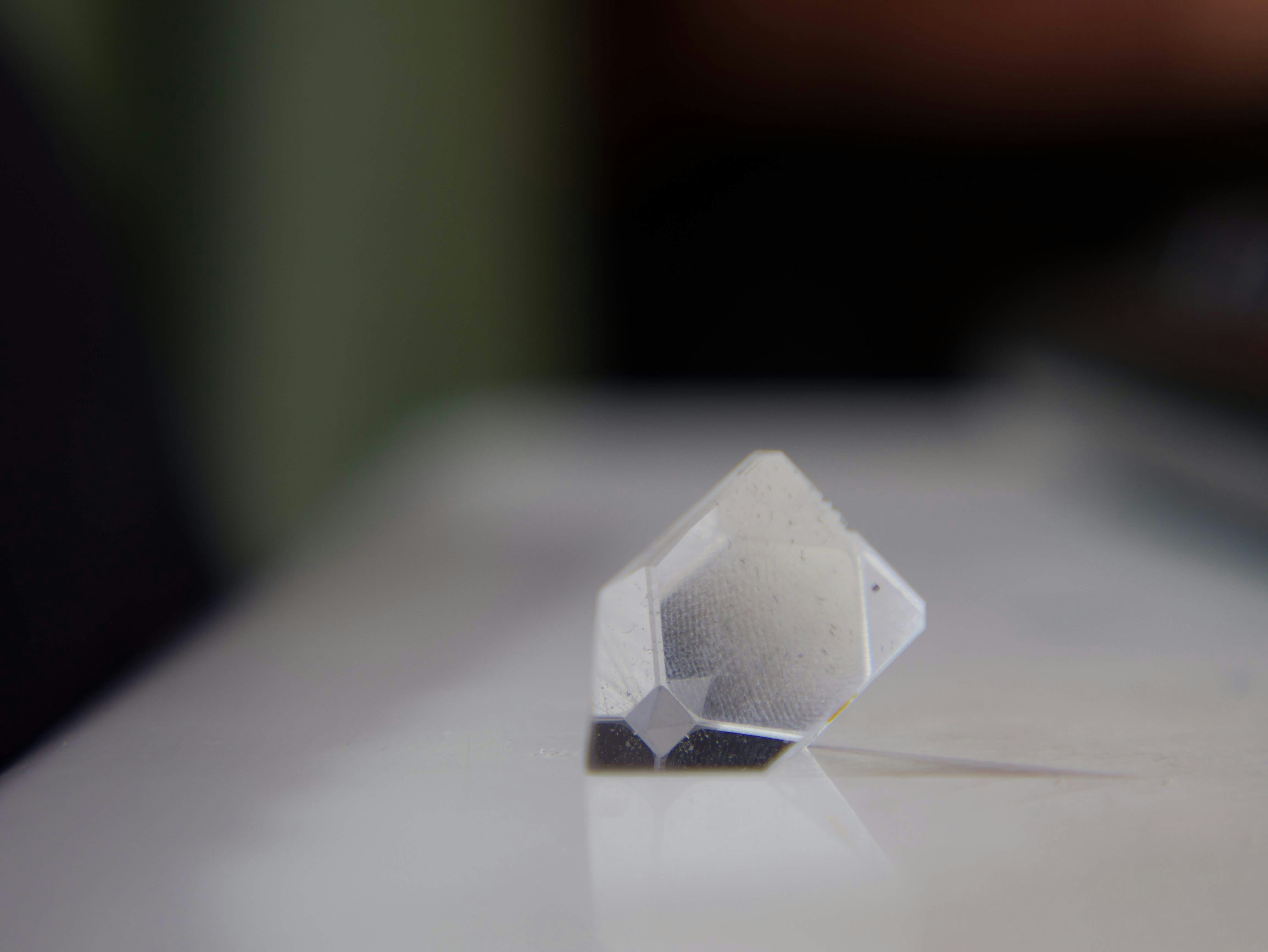 A clear geometric crystal on a white surface